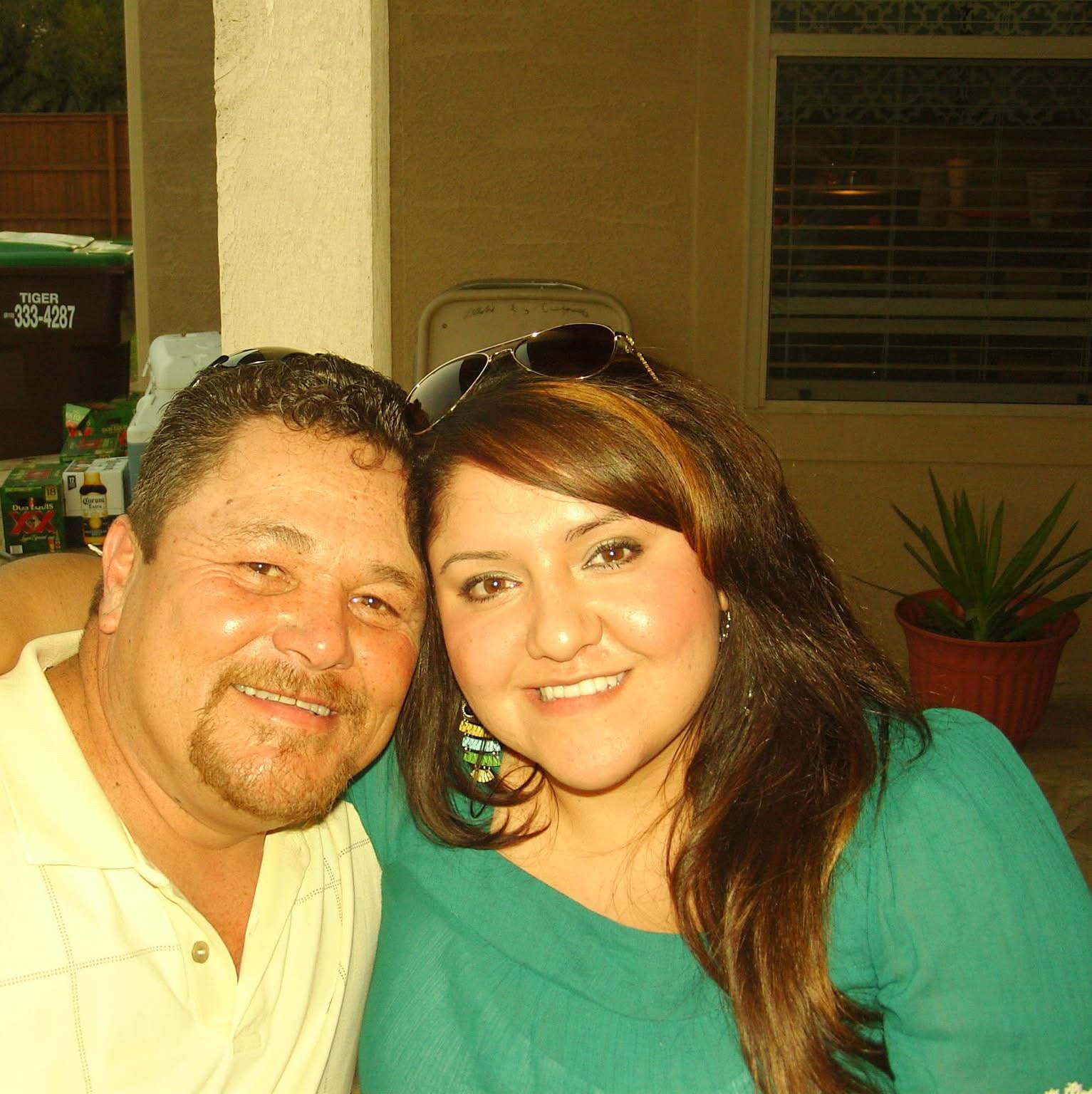 Two people smiling, close-up portrait, woman with long brown hair wearing a green top, man with short dark hair in a light-colored shirt.