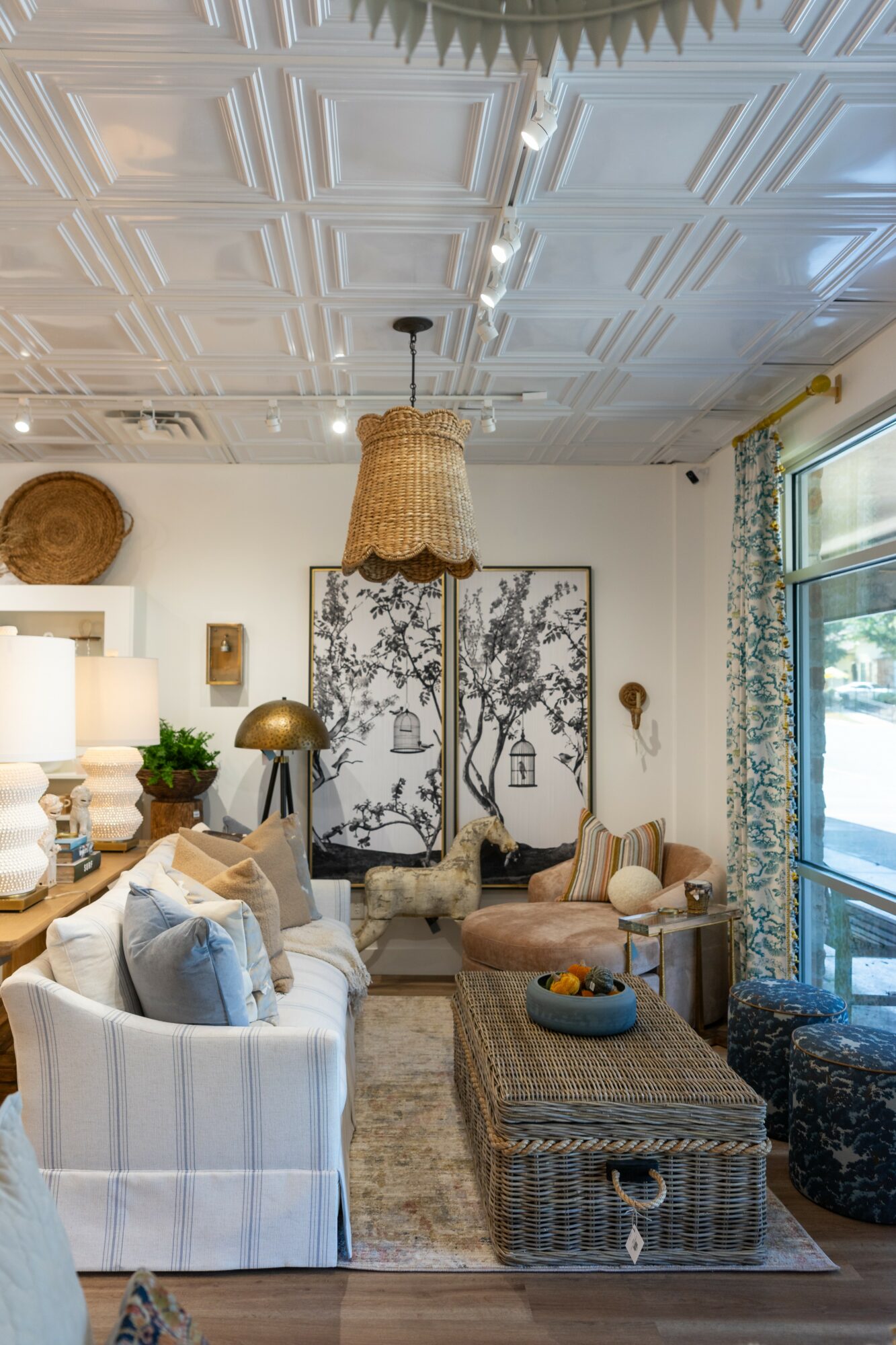 Living room with white sofa, wicker coffee table, large artwork of trees, and various lamps and decor items.
