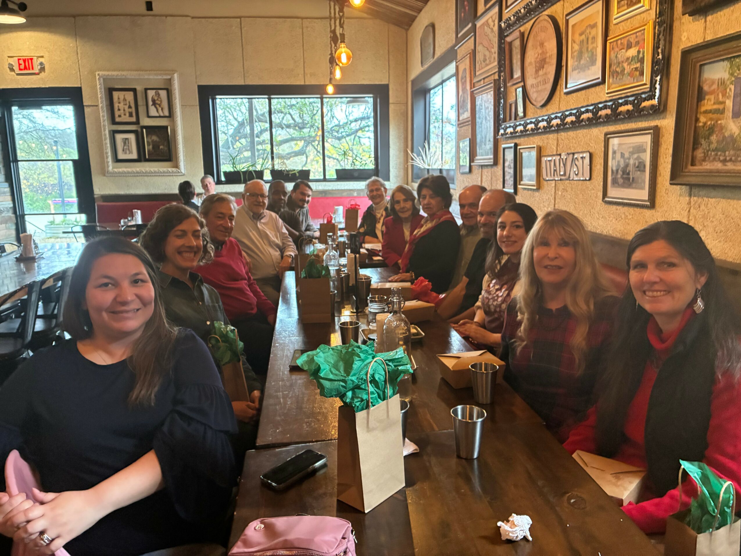 Group of people sitting around a long table in a restaurant, smiling and posing for the photo.