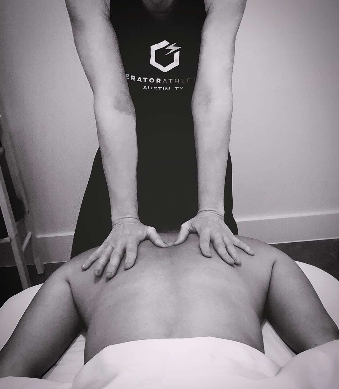 Person receiving a massage on their back from a massage therapist in a room.