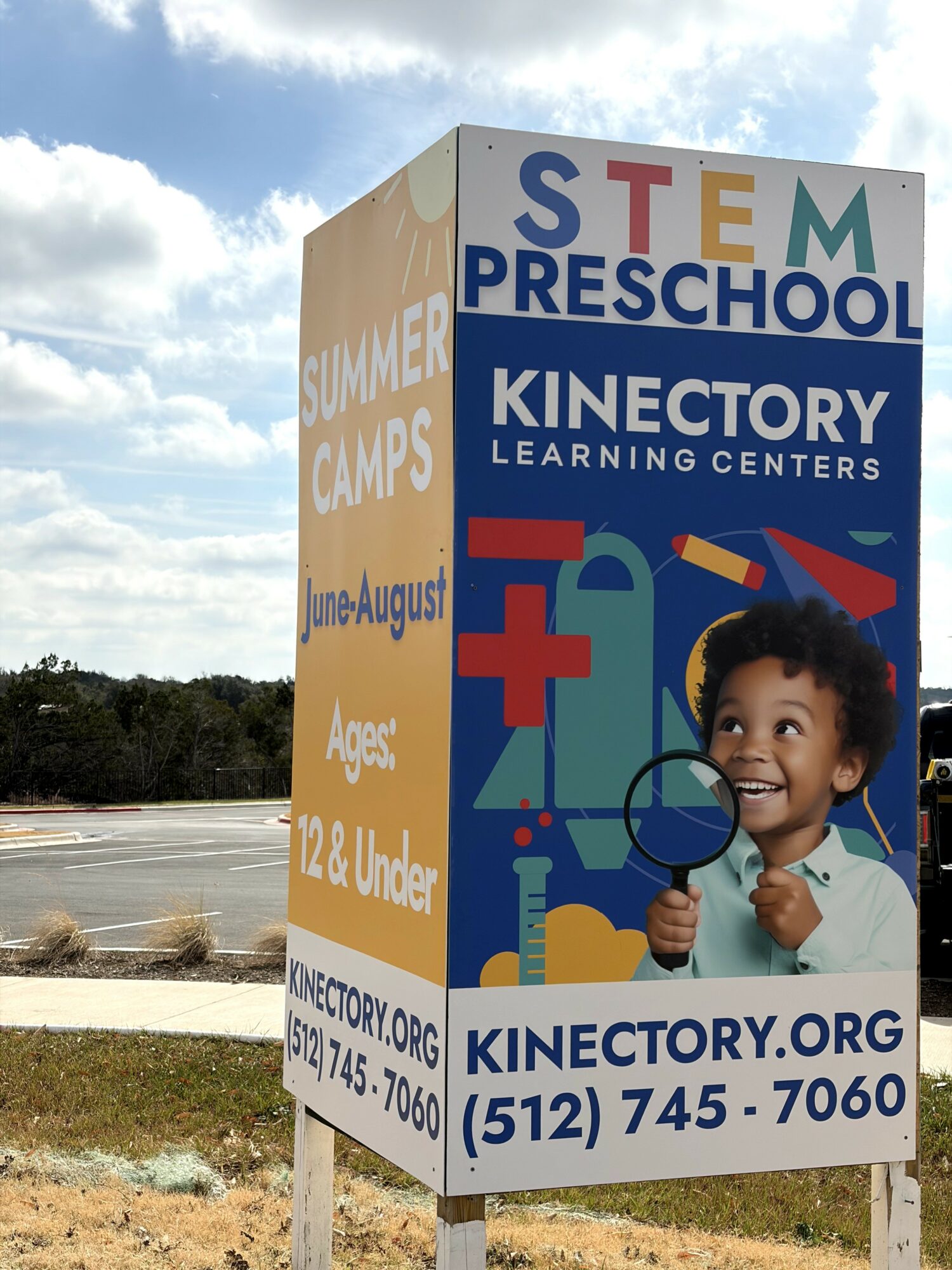 Sign advertising STEM preschool and summer camps with a child holding a magnifying glass, smiling outdoors.