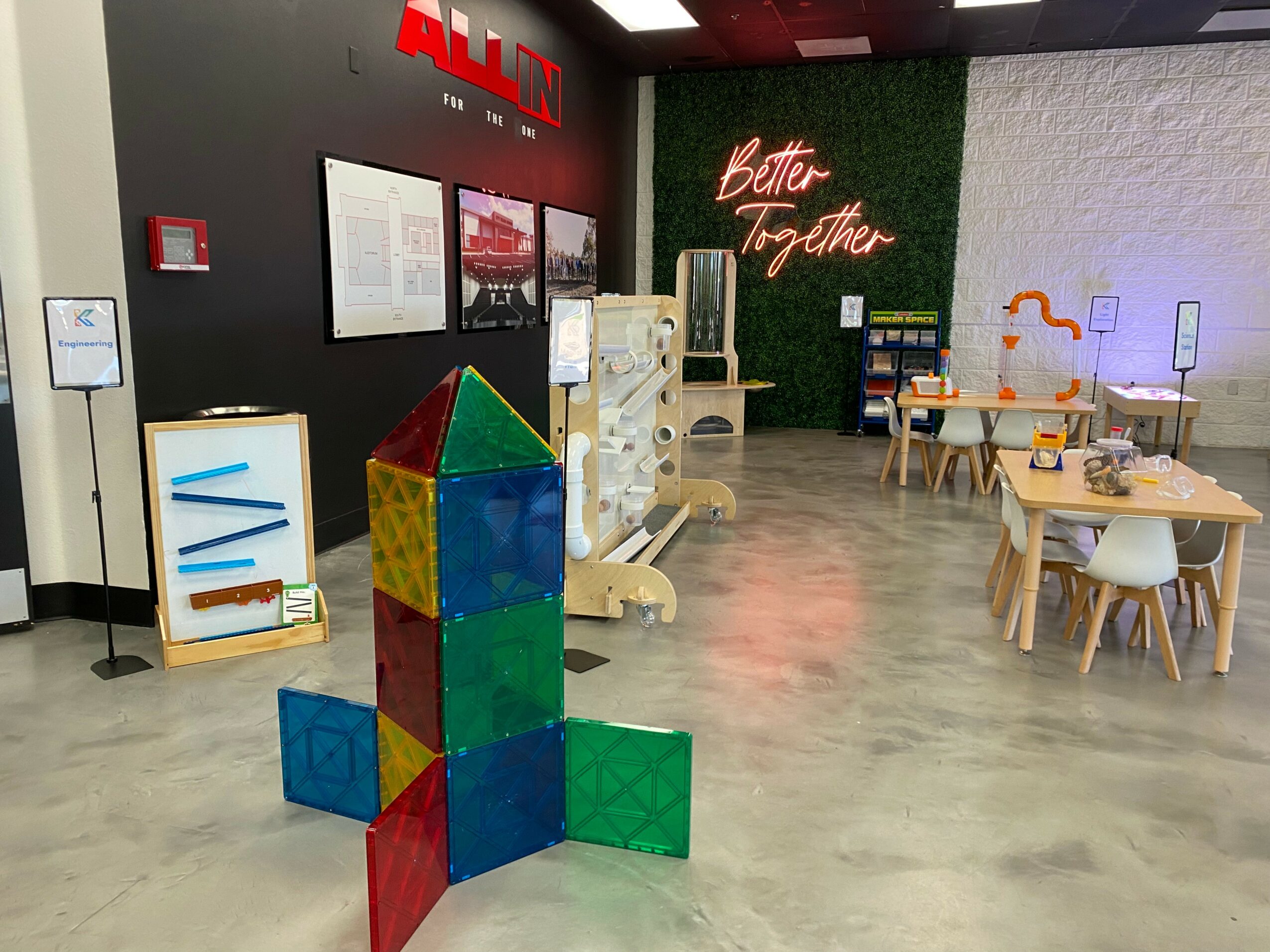 Indoor play area with colorful geometric blocks, a table with chairs, and wall decorations including 'Better Together' sign.