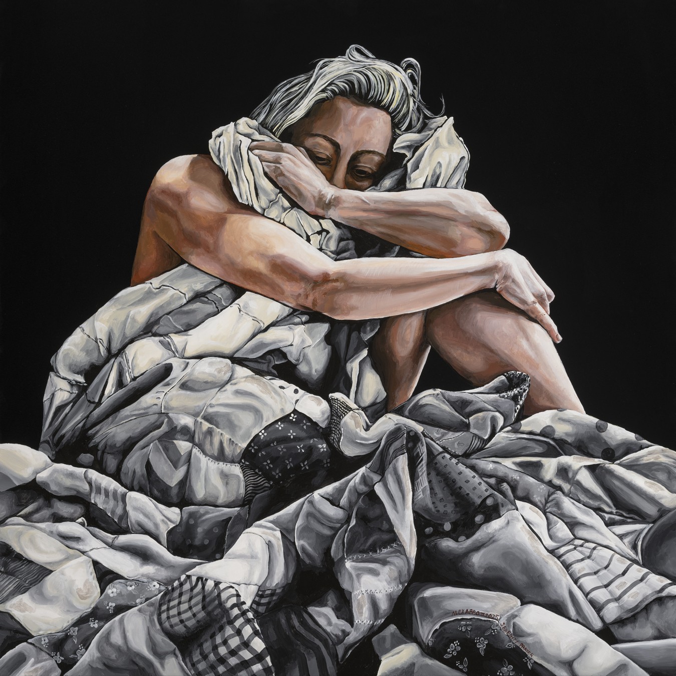 Person with gray hair hugging their knees, sitting on a pile of fabric, against a black background.