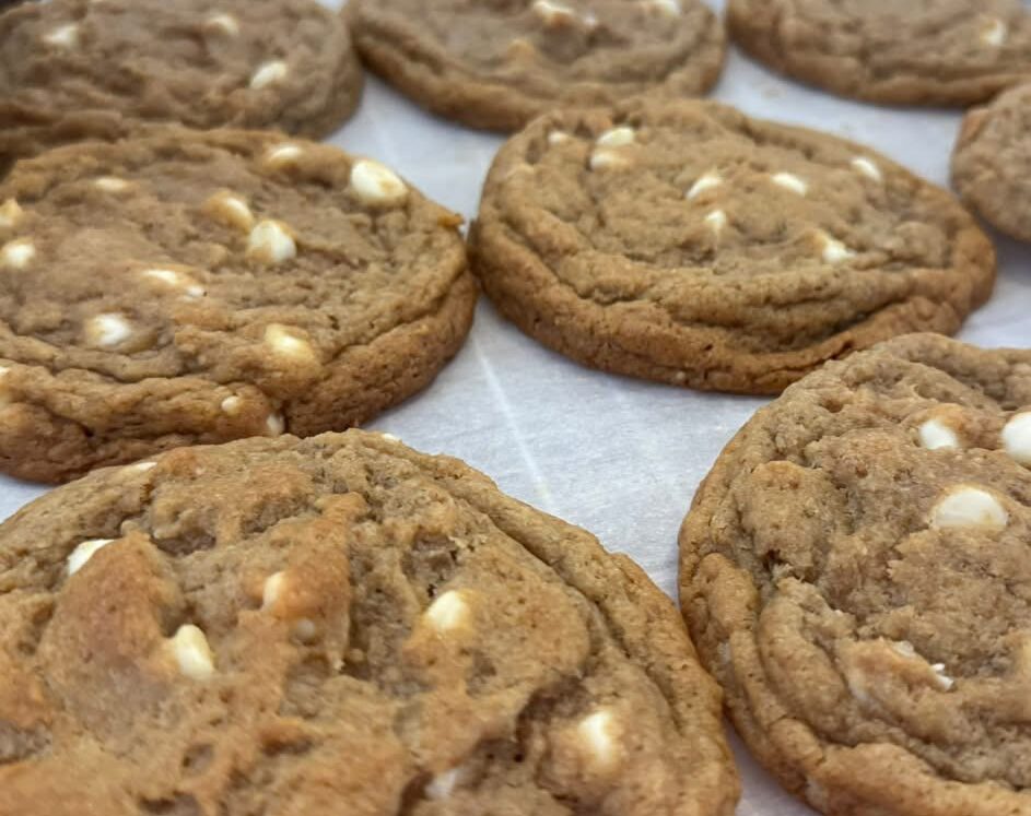 Close-up of chocolate chip cookies with white chocolate chips on a baking sheet.
