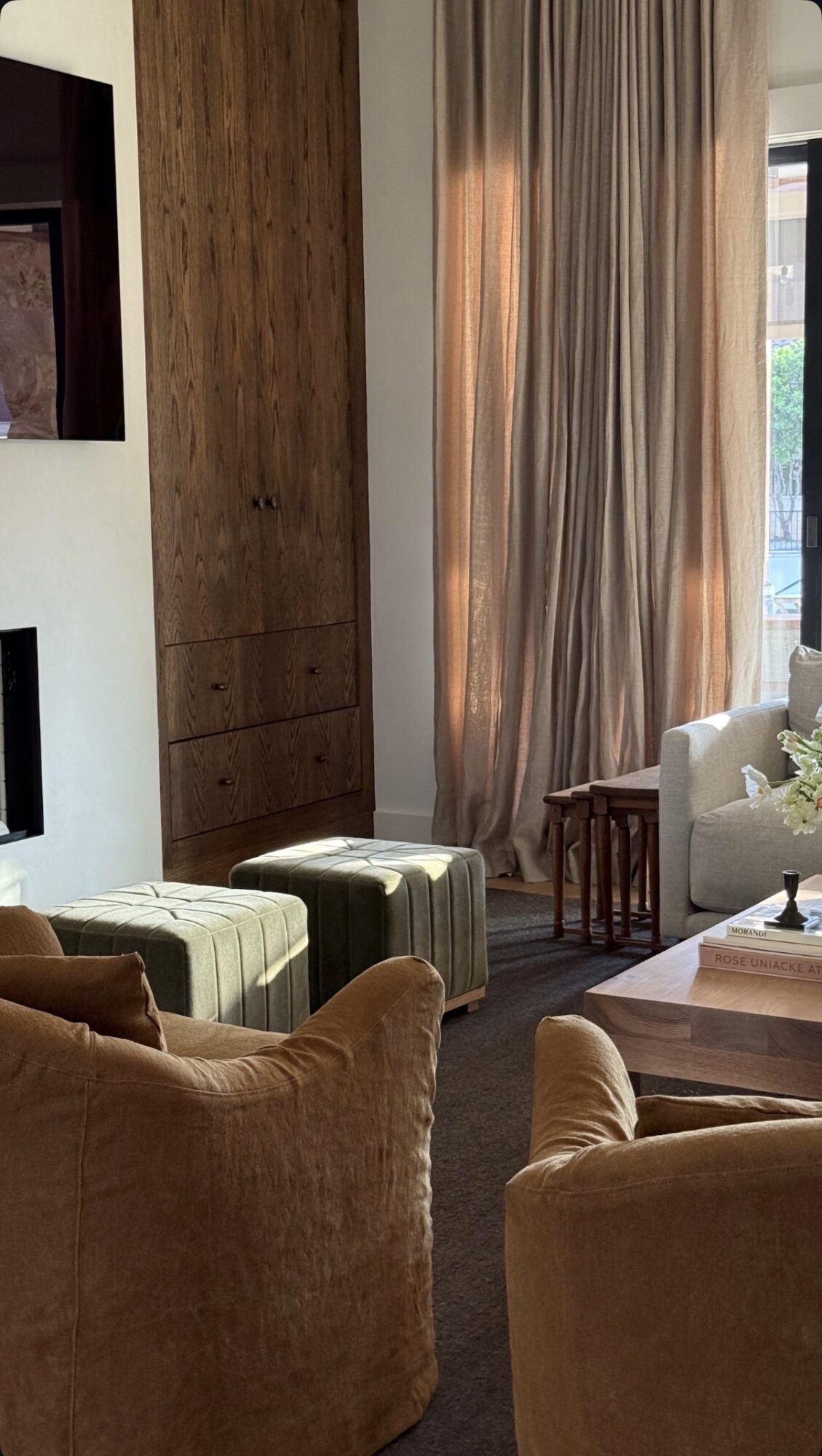 Living room with beige and brown furniture, large window with curtains, and a wooden side table.