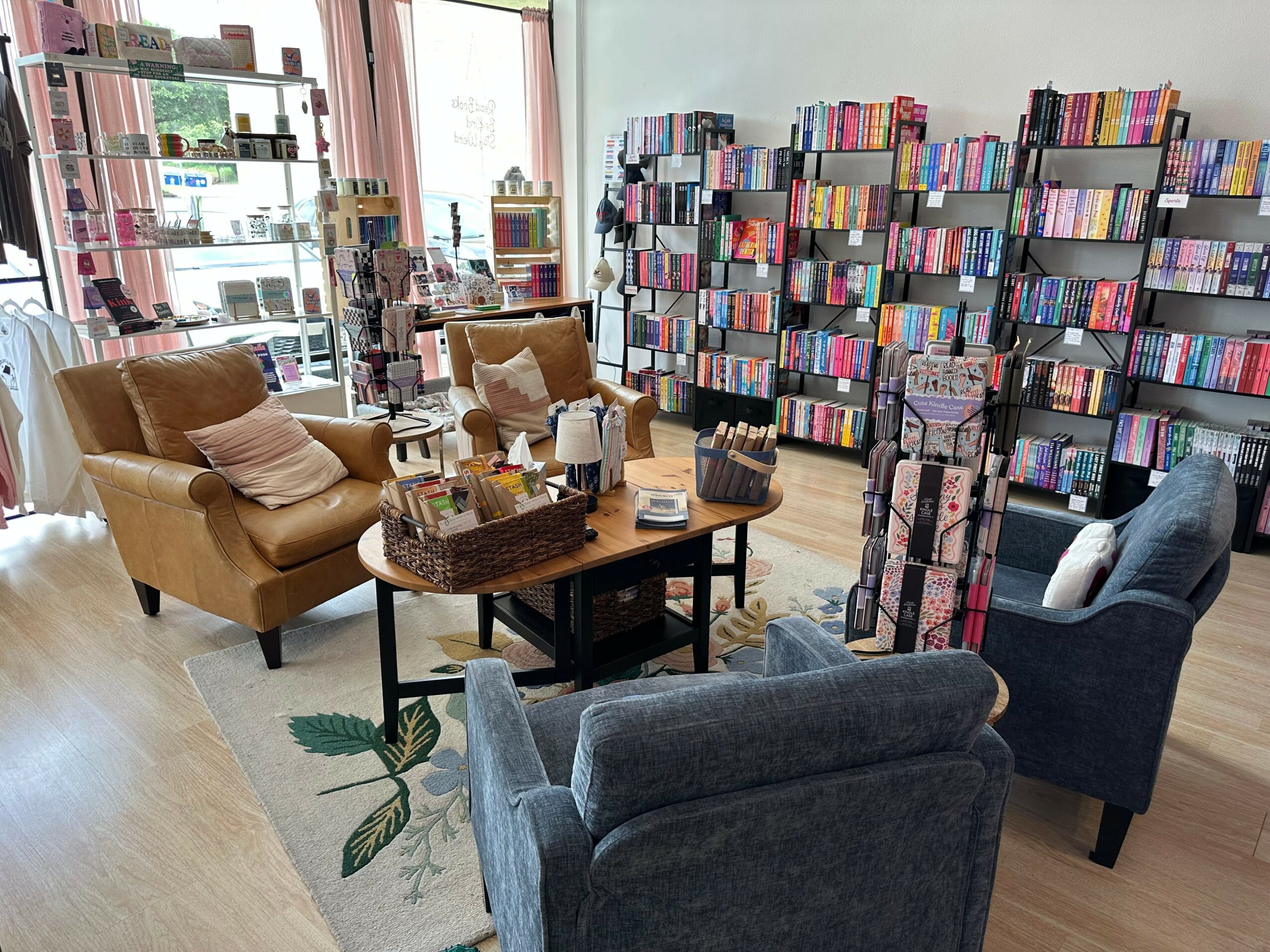 Bookstore or library with shelves filled with books, seating area with armchairs, and a table in the center.