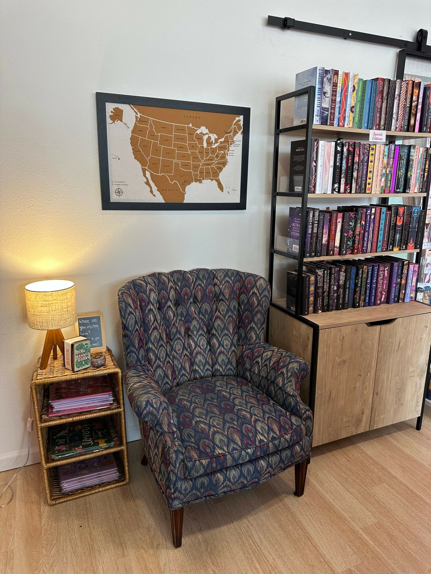 Room with a bookshelf, patterned armchair, small side table, and framed map on the wall.
