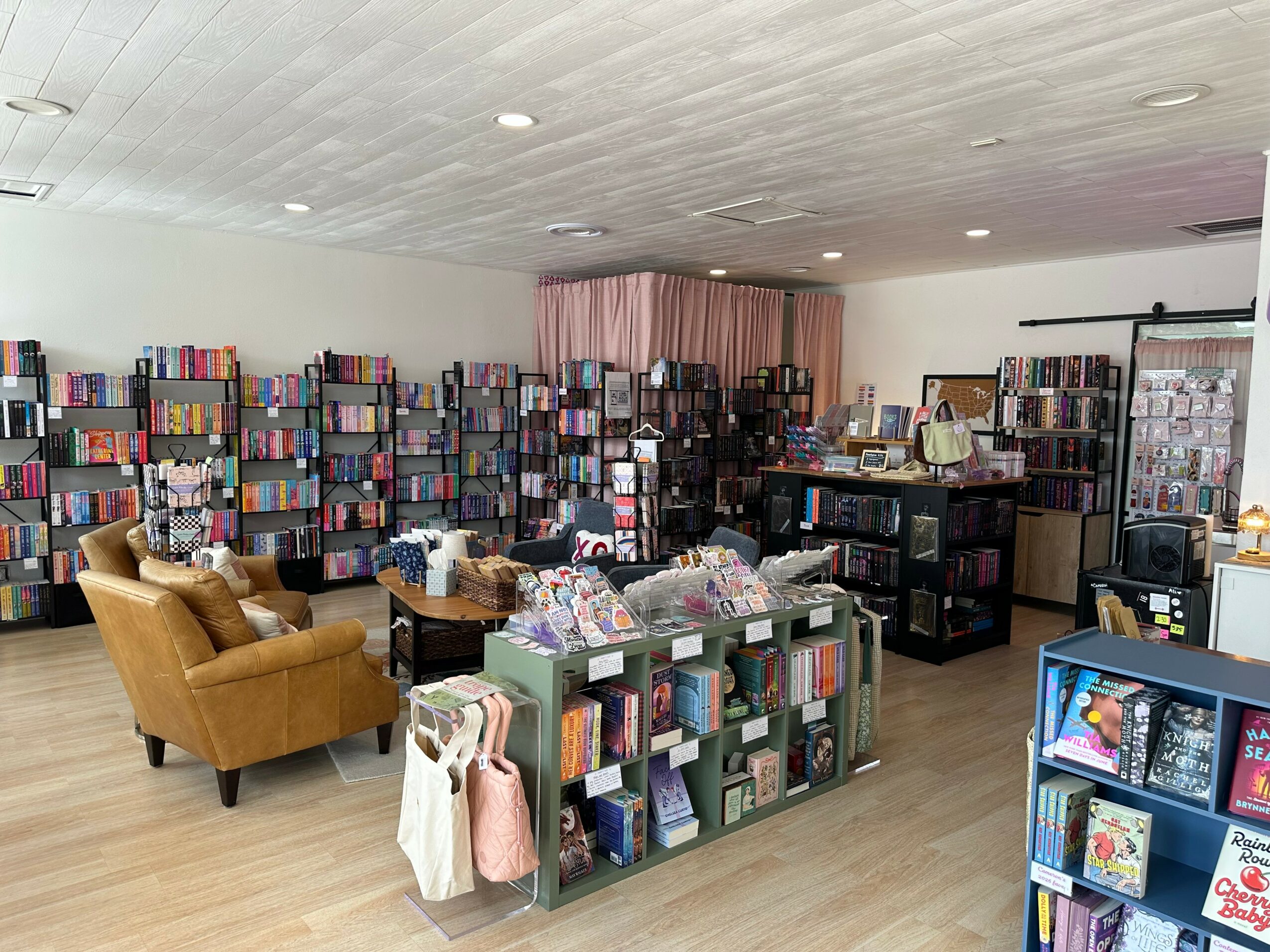 Bookshelves filled with books, a seating area with two yellow armchairs, and a display table in a bookstore.