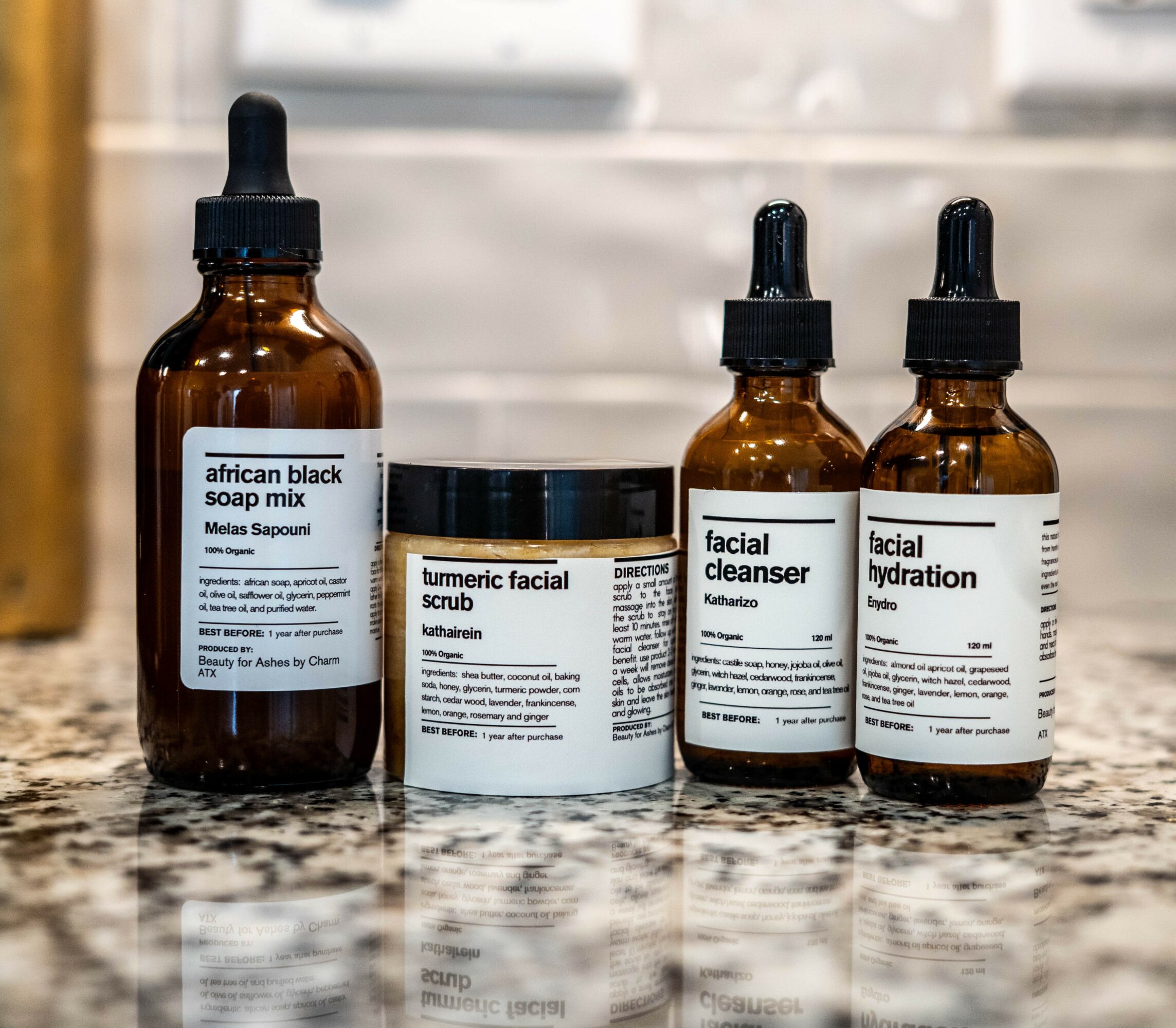 Four skincare product bottles and containers on a marble surface, with labels visible. Background is blurred.