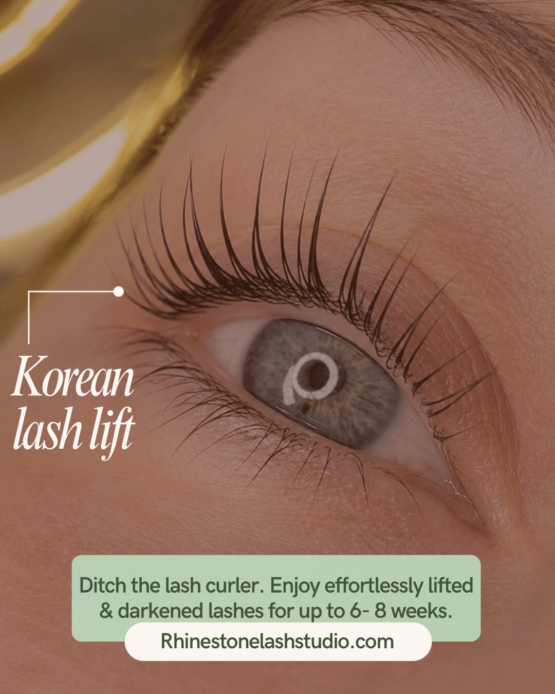 Close-up of a person's eye with long, dark eyelashes and gray iris, with text about Korean lash lift and a website.