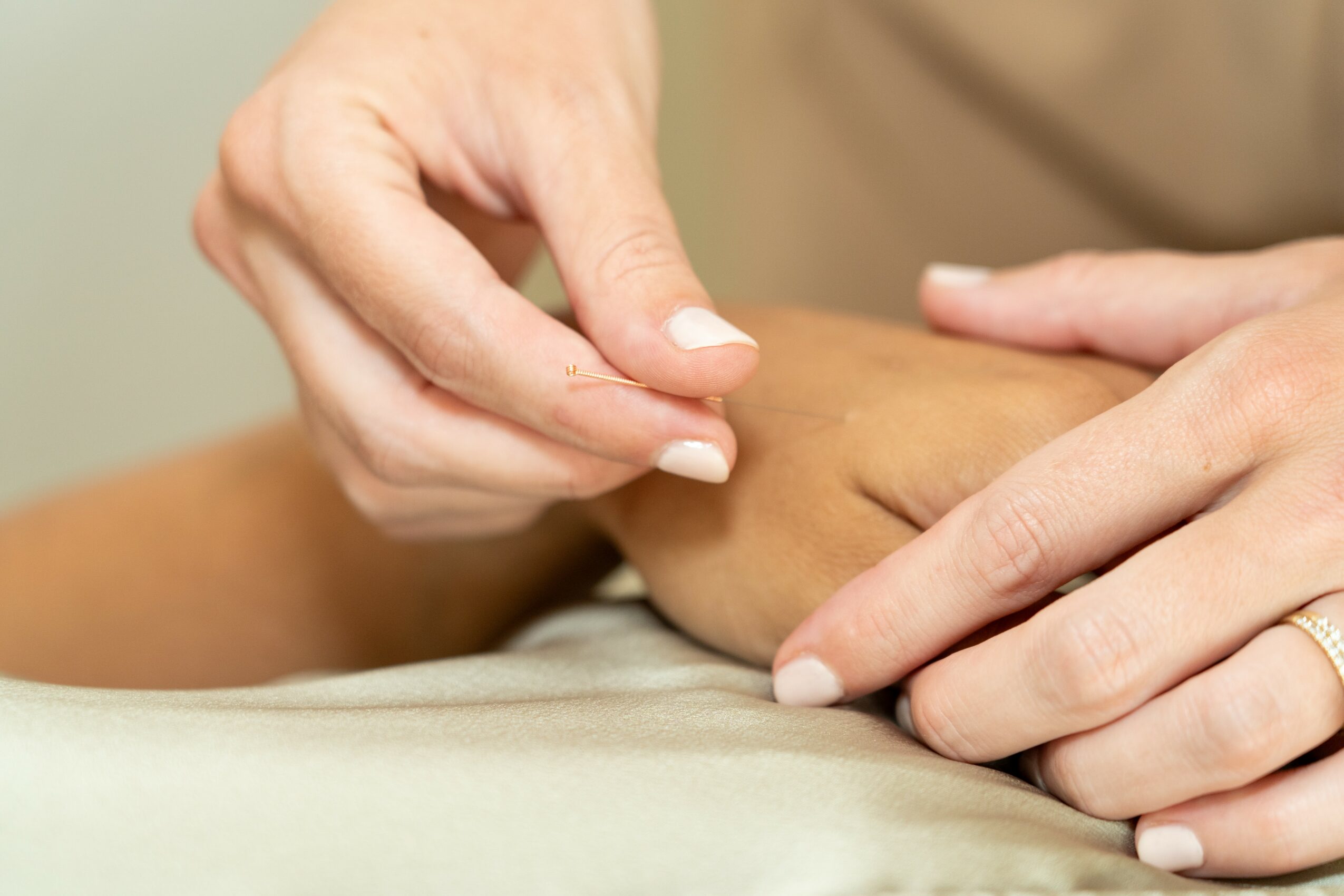 Person's hand pinching skin on another person's arm, with hands resting on a surface.