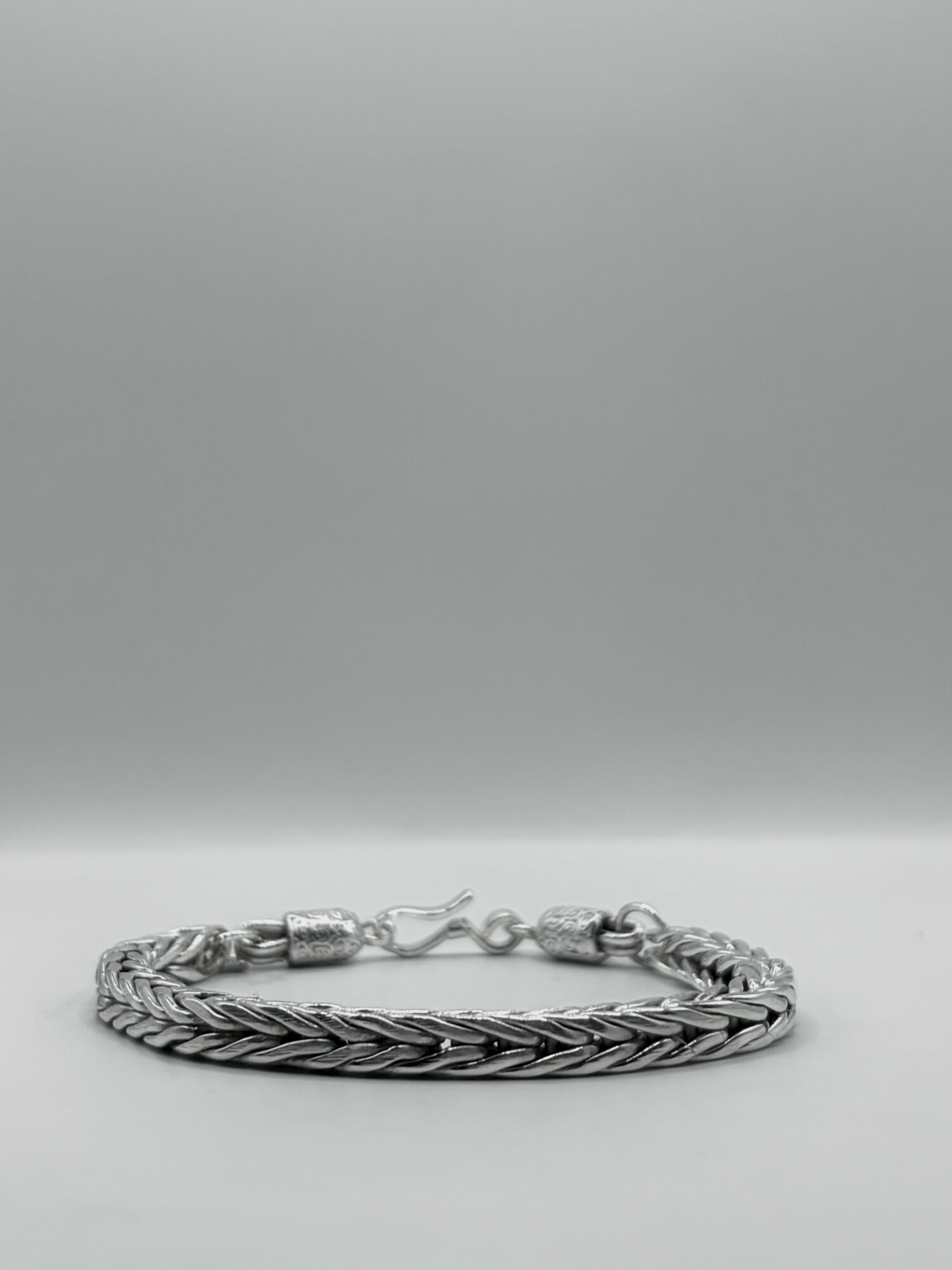 Silver braided bracelet with clasp on a plain background