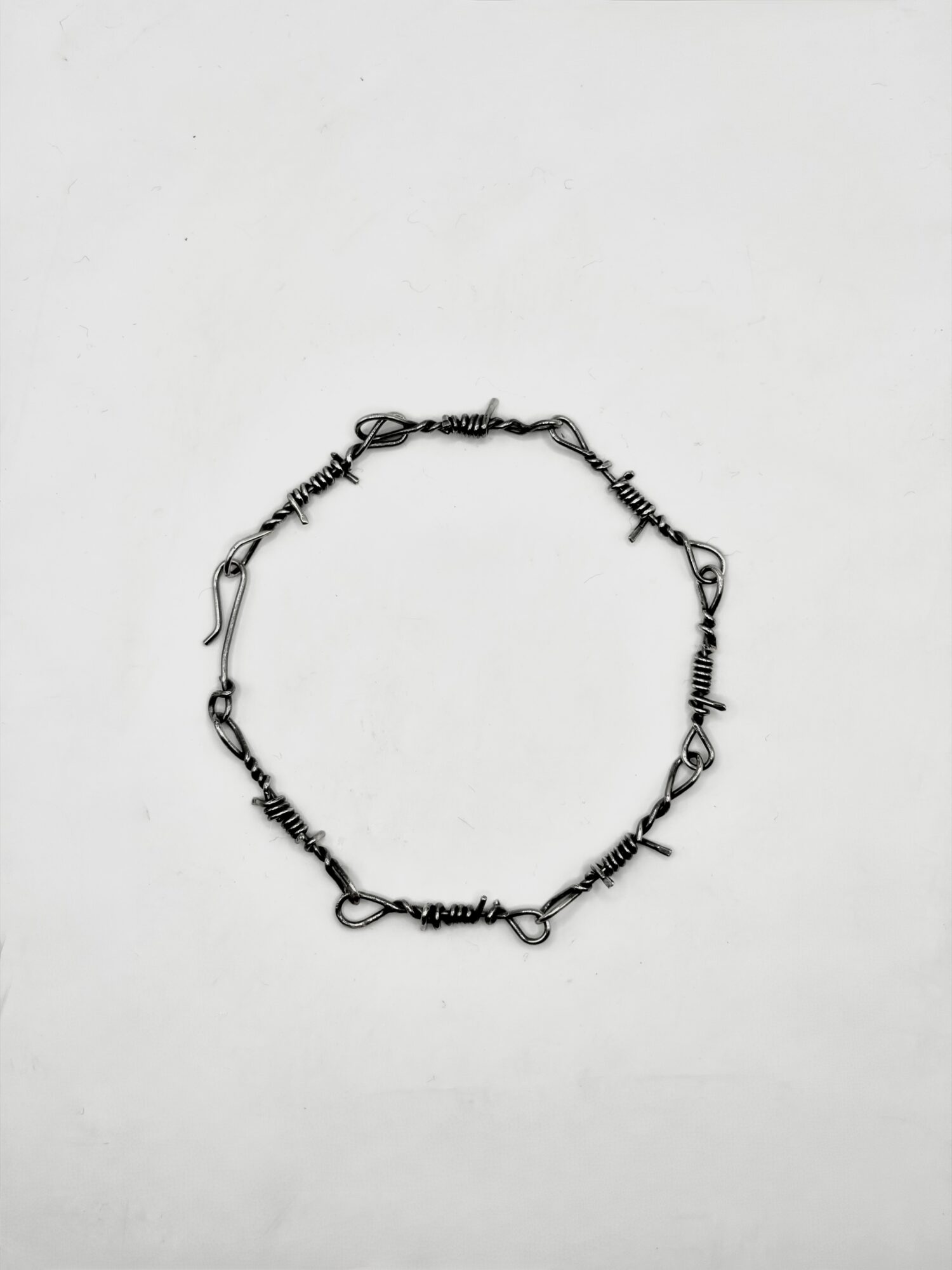 A silver chain bracelet with various links, arranged in a circle on a plain white background.