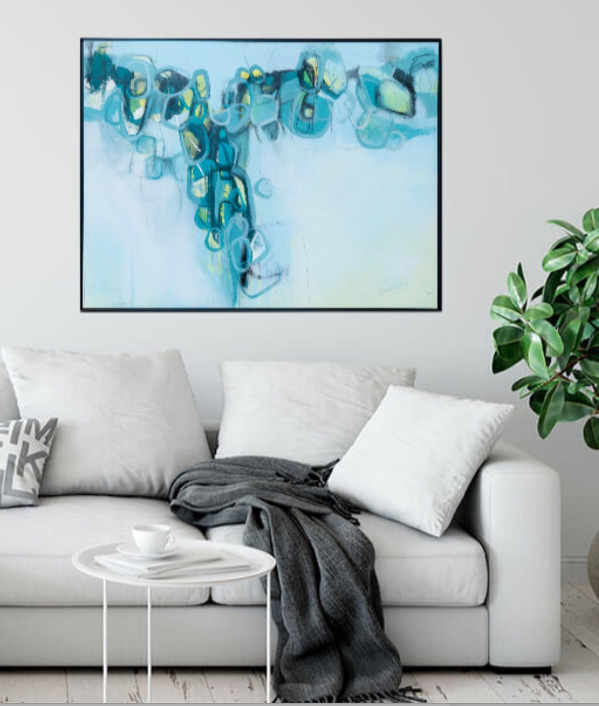 Living room with a white sofa, pillows, a gray blanket, a small white table, and a large abstract blue painting on the wall.