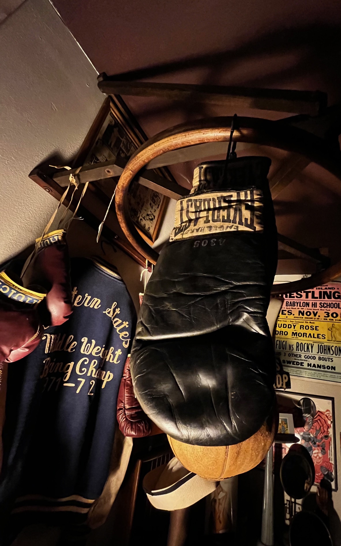 A black leather chair hanging upside down in a room with posters and furniture, viewed from below.