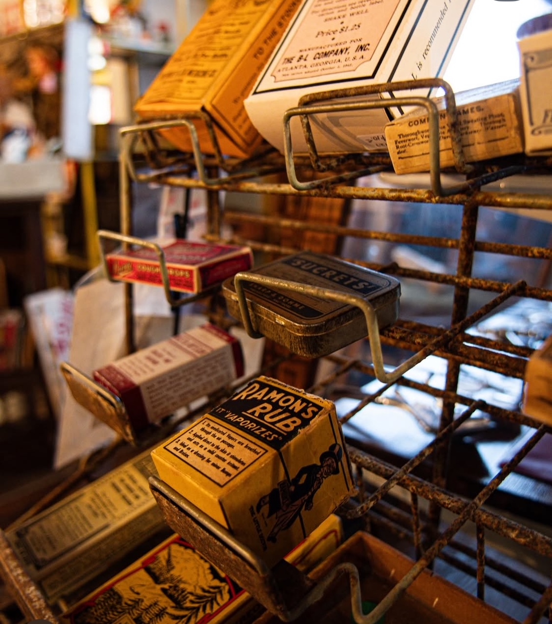 Close-up of vintage matchbooks and boxes on a metal rack in a store, with blurred background. Word 'RAMONES' visible.