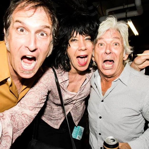 Three people with surprised expressions, close together, in an indoor setting.
