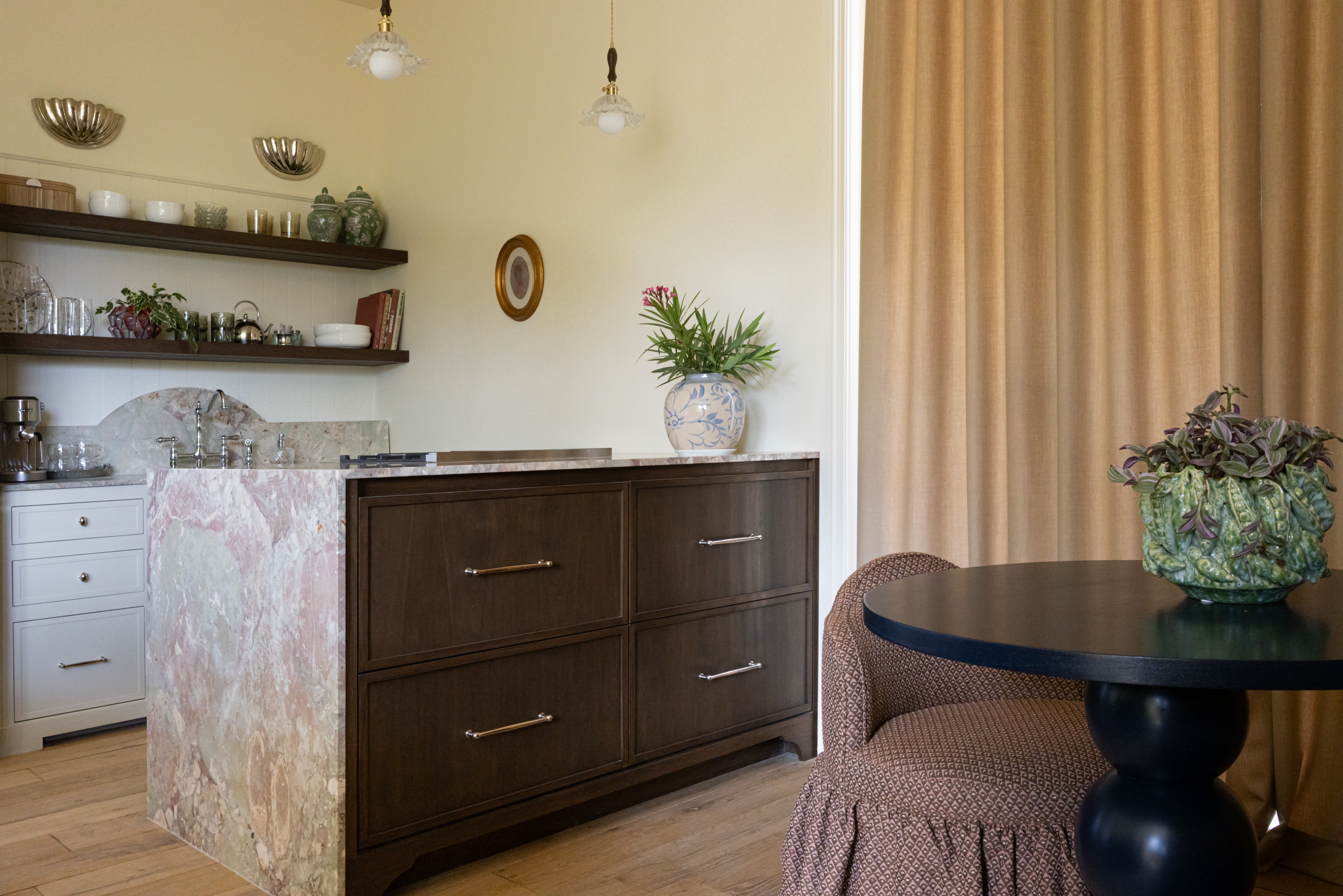 Living room with a dark wooden sideboard, a round table with a flower arrangement, and beige curtains.