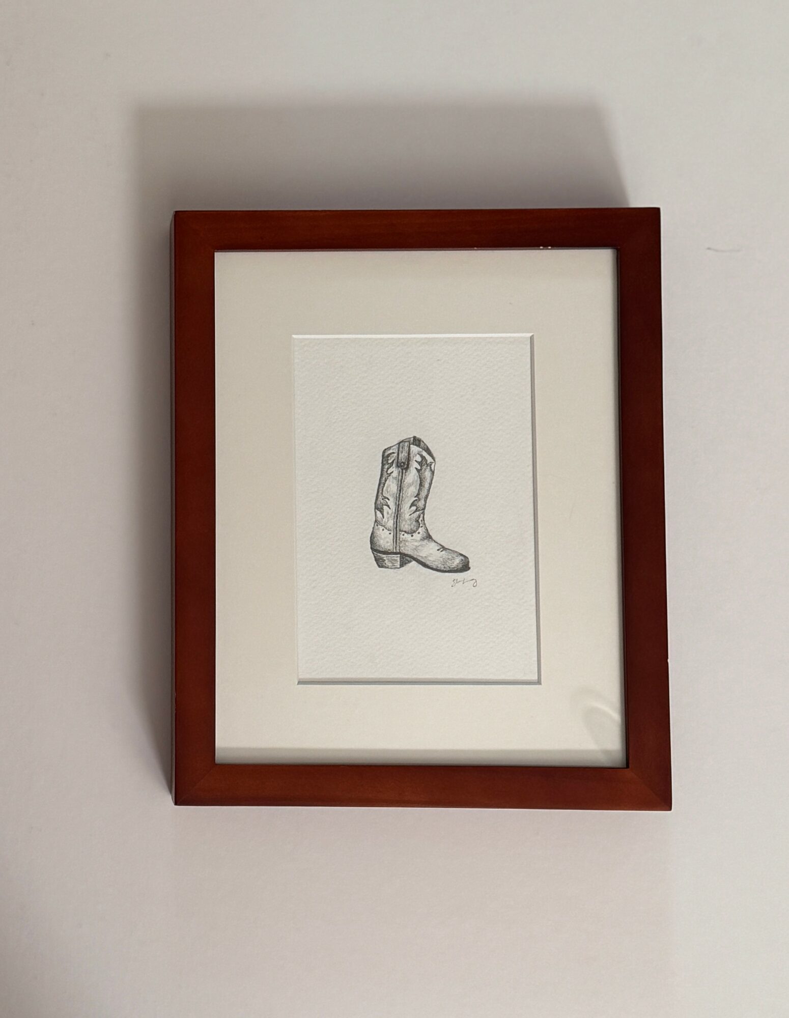 Drawing of a boot inside a wooden frame on a wall.
