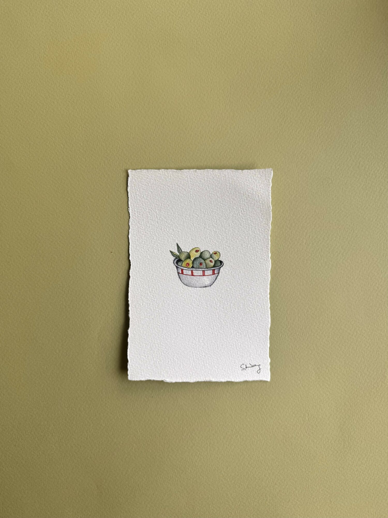 Small illustration of a bowl filled with blueberries and a few green leaves, on white paper with torn edges.