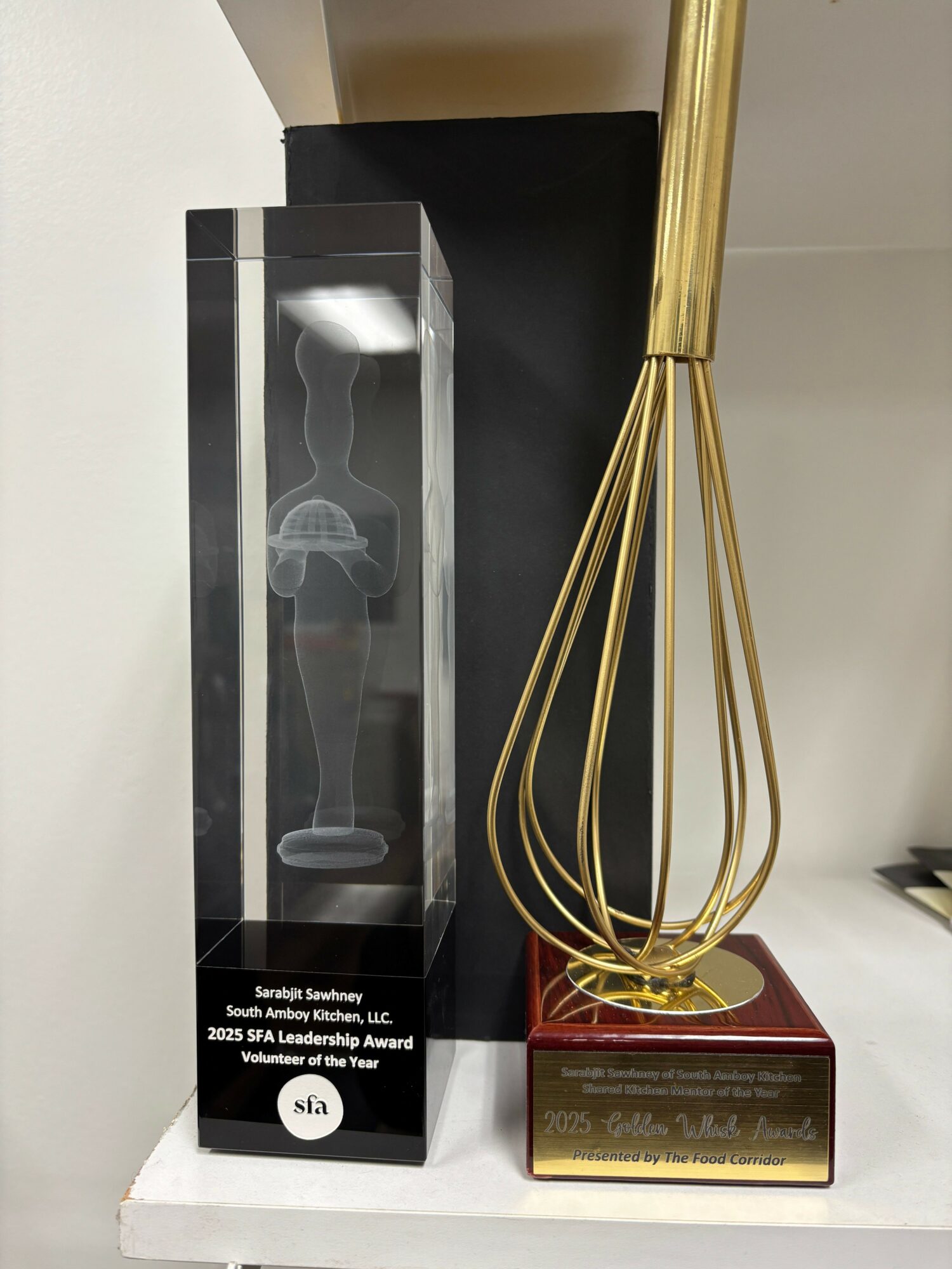 Golden decorative object with a red base, placed on a white surface, with a black box behind it.
