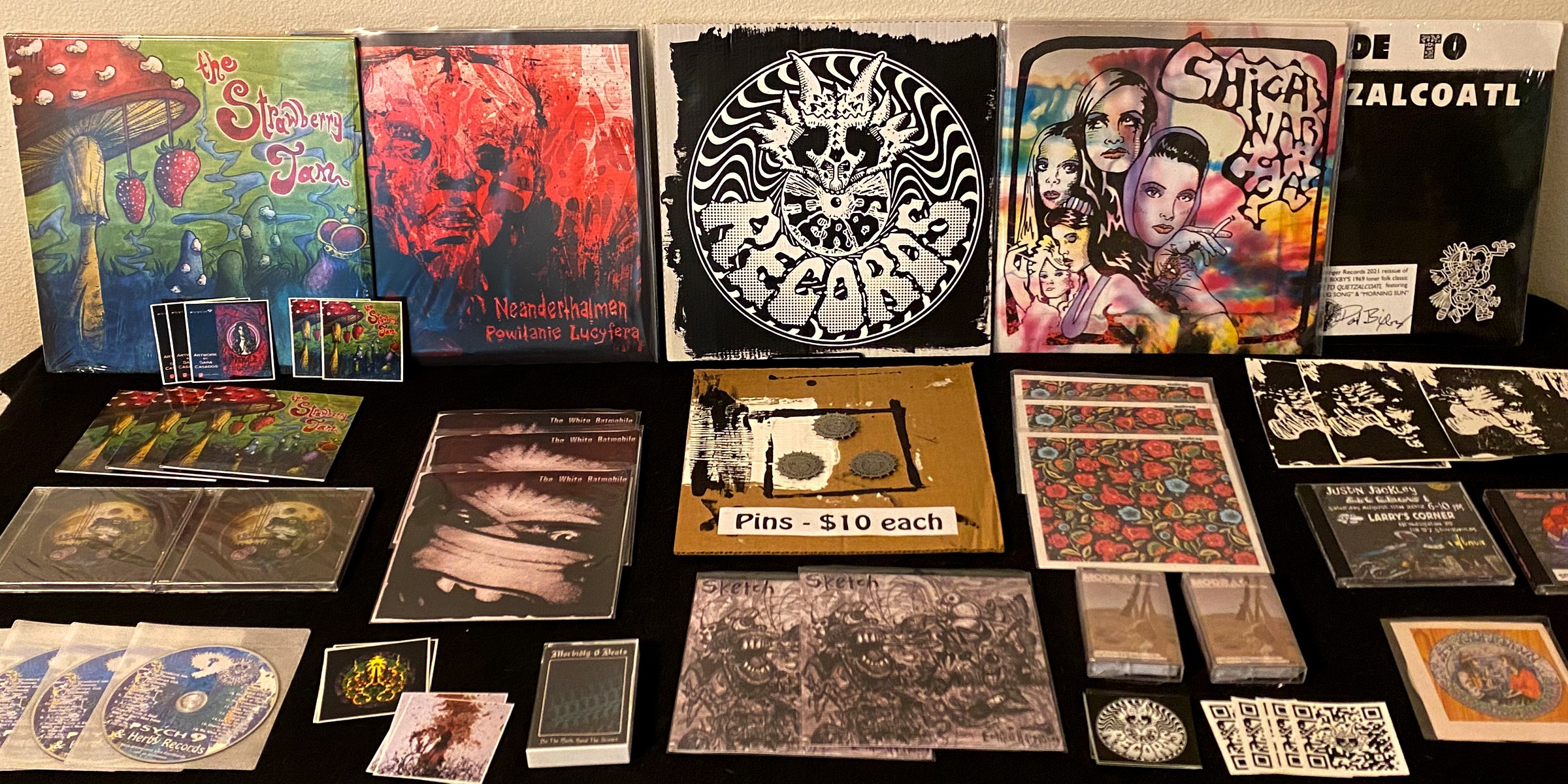 Collection of vinyl records, CDs, and album covers displayed on a table, with colorful and black-and-white artwork.