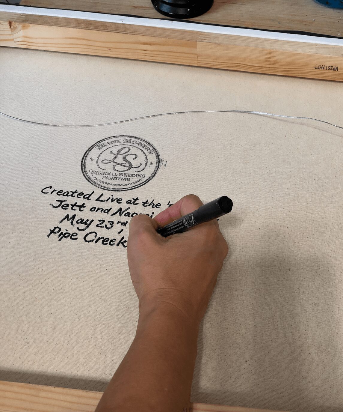 Hand writing on a large sheet of paper with a marker, with a logo and text visible on the paper.