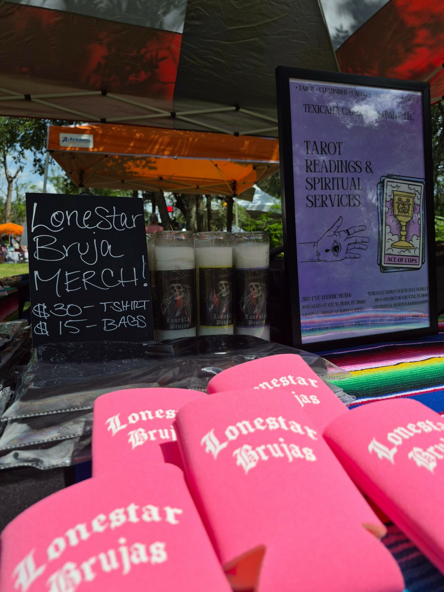 Display with pink promotional items, a blackboard sign, and a framed certificate or poster, outdoors with trees and sky visible.