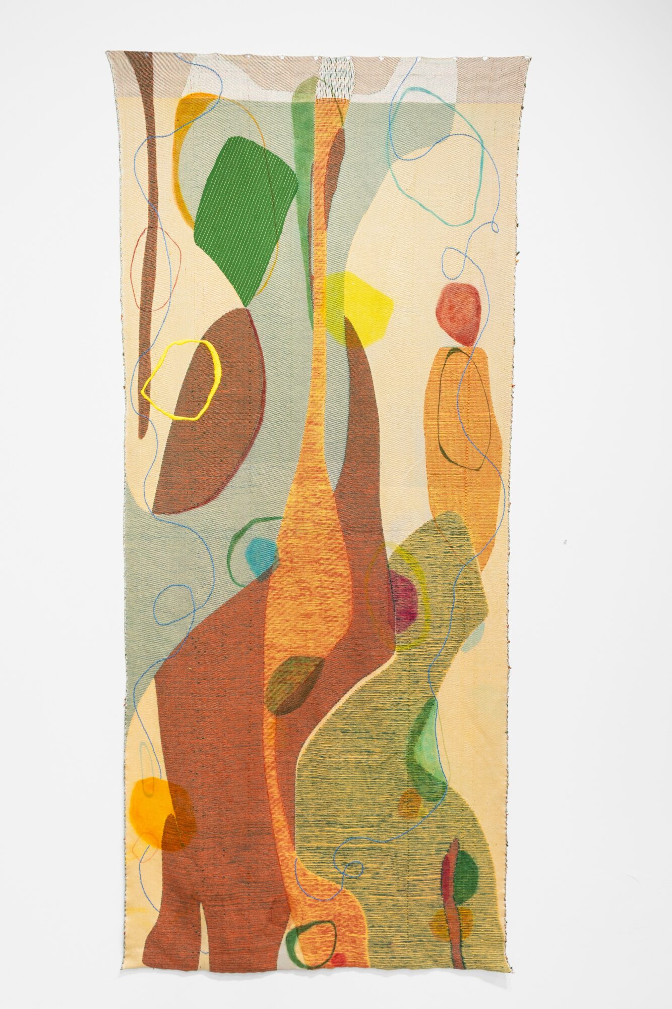 Abstract fabric with colorful shapes and lines, including green, yellow, orange, and brown, on a light background.