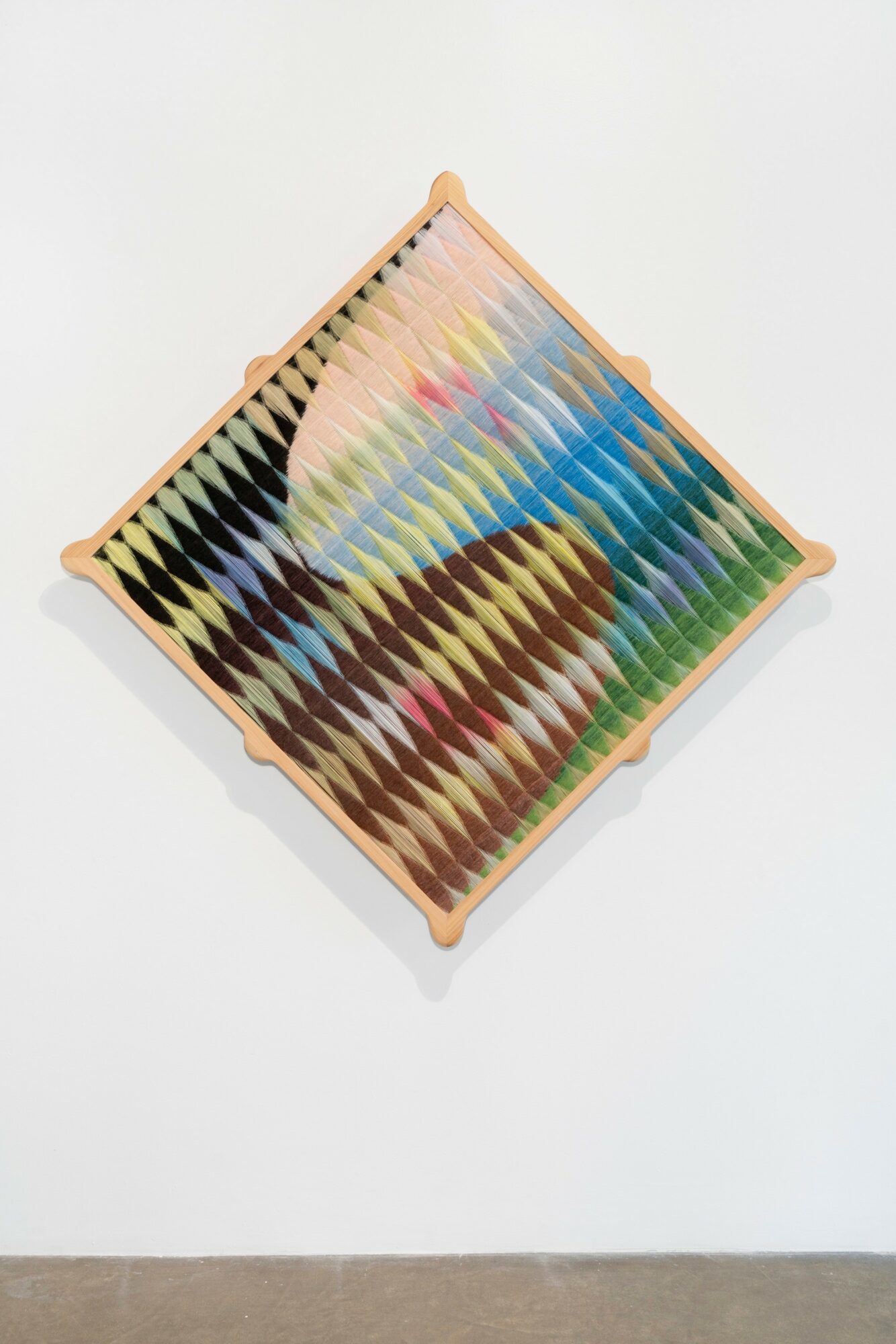 Colorful geometric pattern on a square tray with a wooden border, viewed from above, on a white wall background.