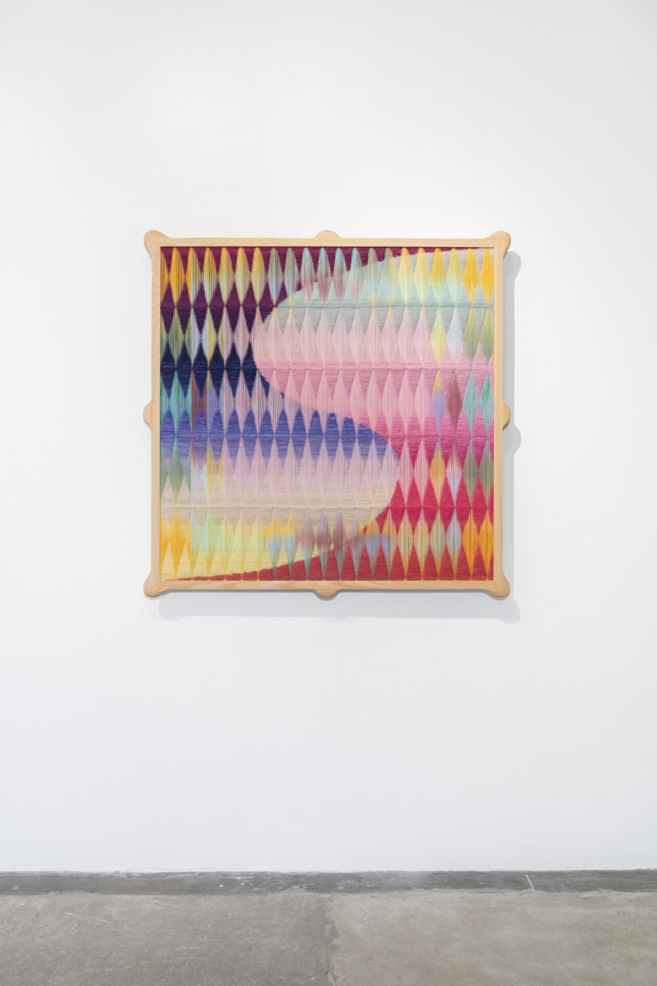 Colorful abstract artwork with diamond shapes and a flowing pattern on a white wall.