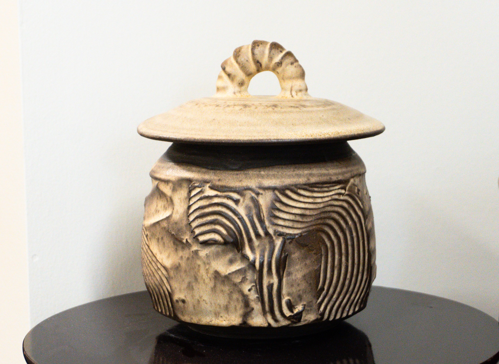 Decorative carved wooden container with a lid and a handle, placed on a dark surface against a white background.