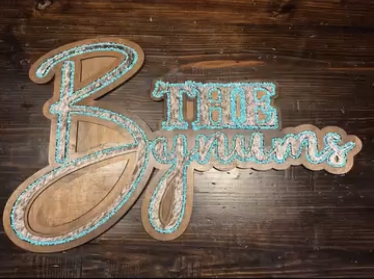 Decorative sign with the words 'The Bryants' in cursive, placed on a wooden surface.