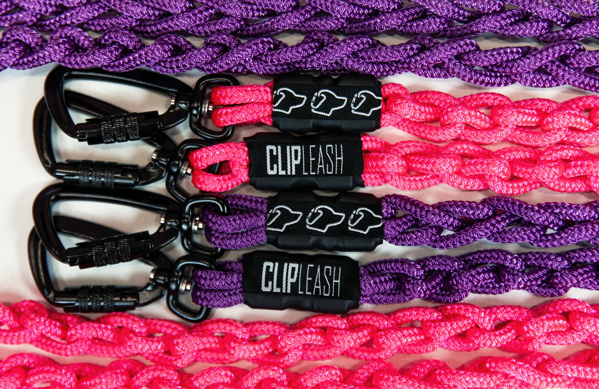 Multiple colorful woven straps with clips and black labels reading 'CLIPLEASH' arranged horizontally.
