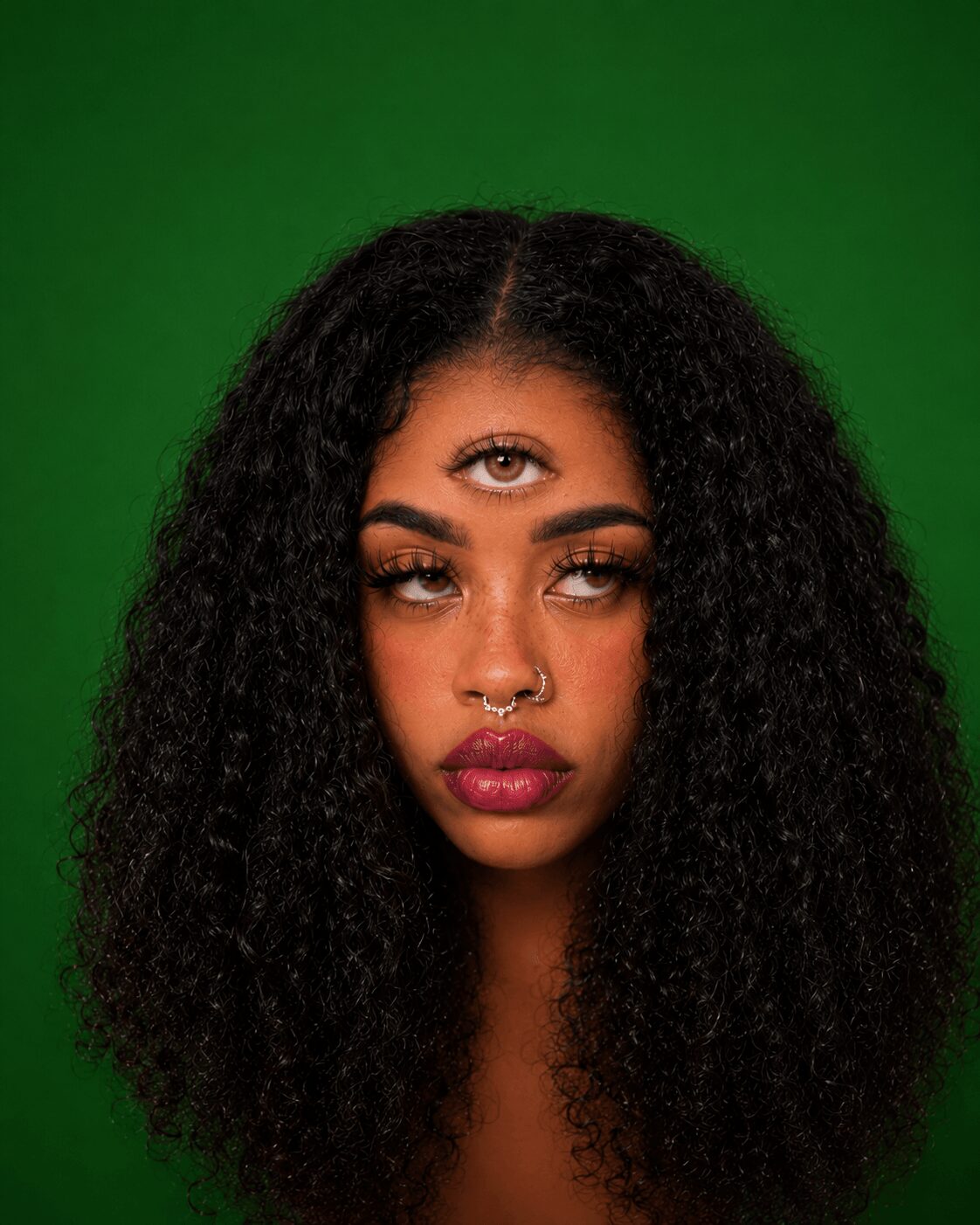 Woman with curly hair and makeup, looking at camera against green background.