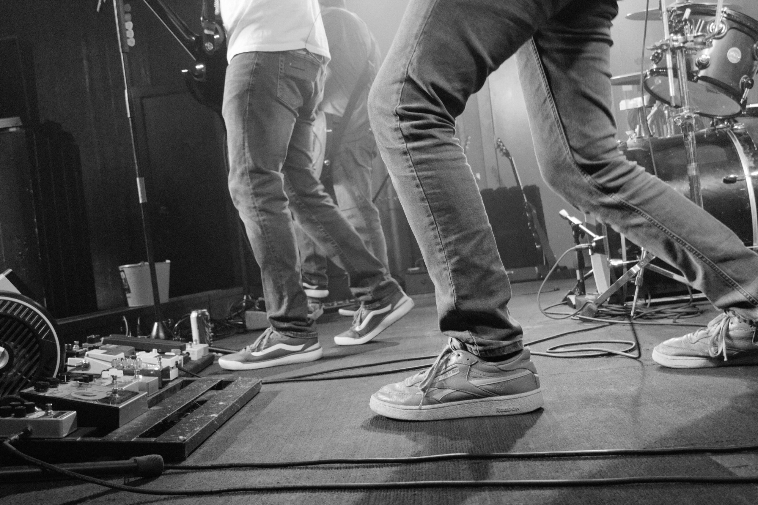 People standing and walking on a stage with equipment and cables, in black and white.