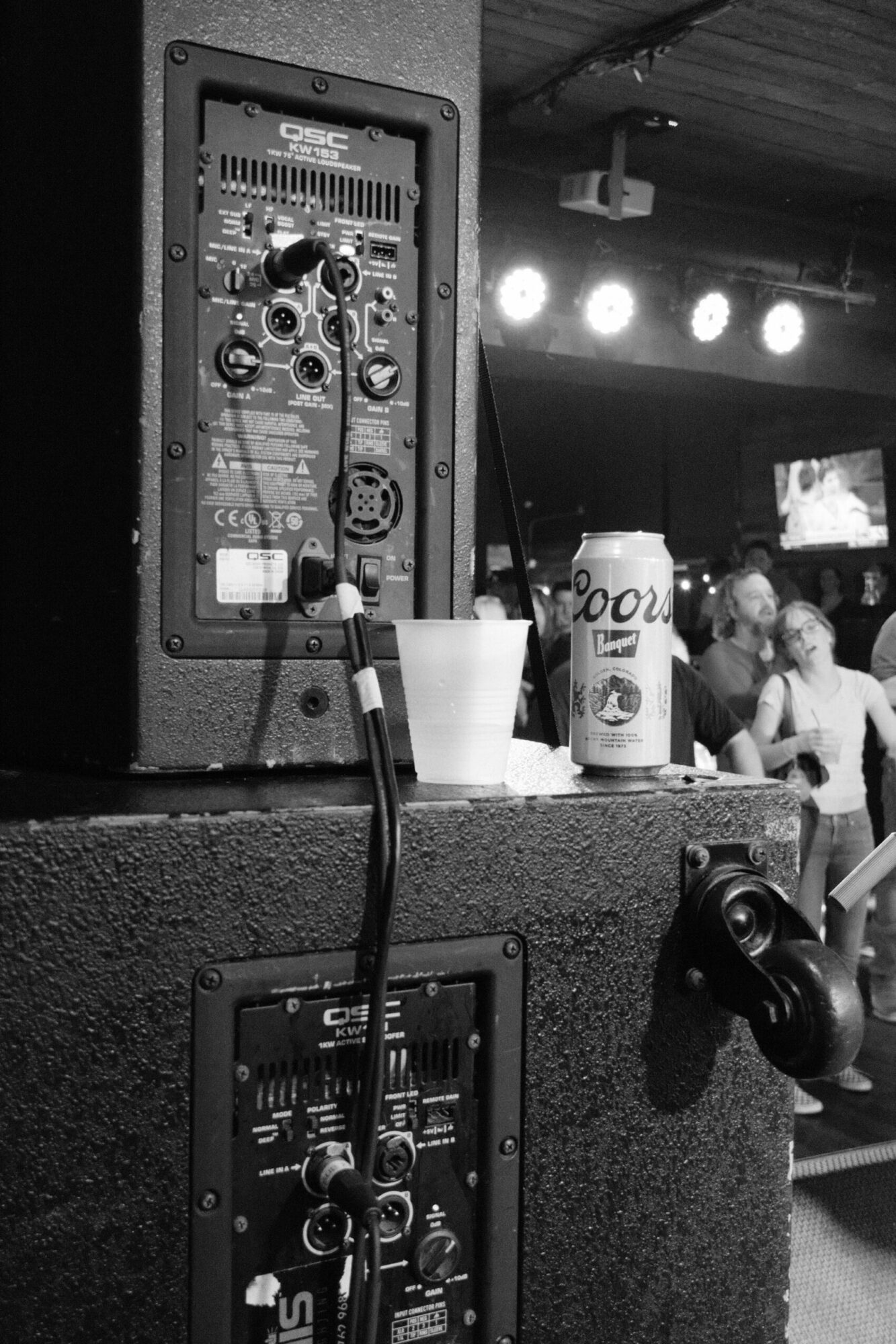 View of electronic equipment with cables, a bottle, and a person in the background, illuminated by bright lights.