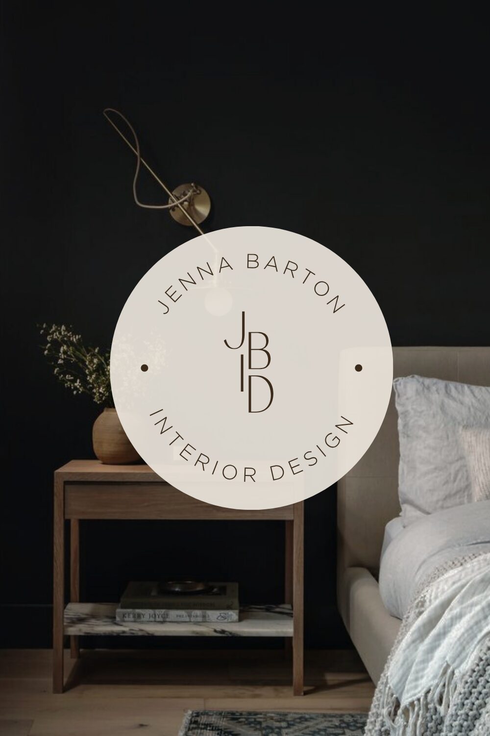 Round white sign with text and logo hanging on a string, next to a wooden table and bed in a bedroom.