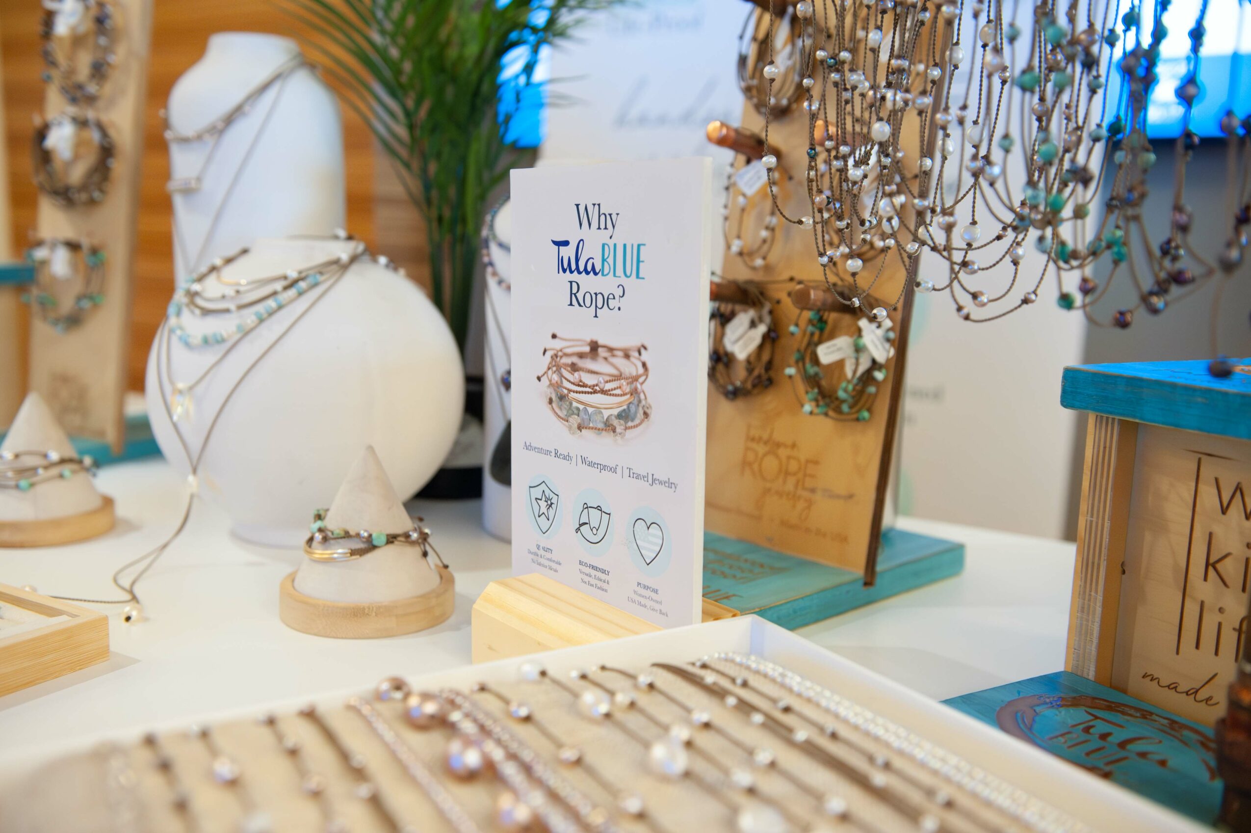 Jewelry display with necklaces and bracelets, a sign about jewelry, and decorative items on a table.