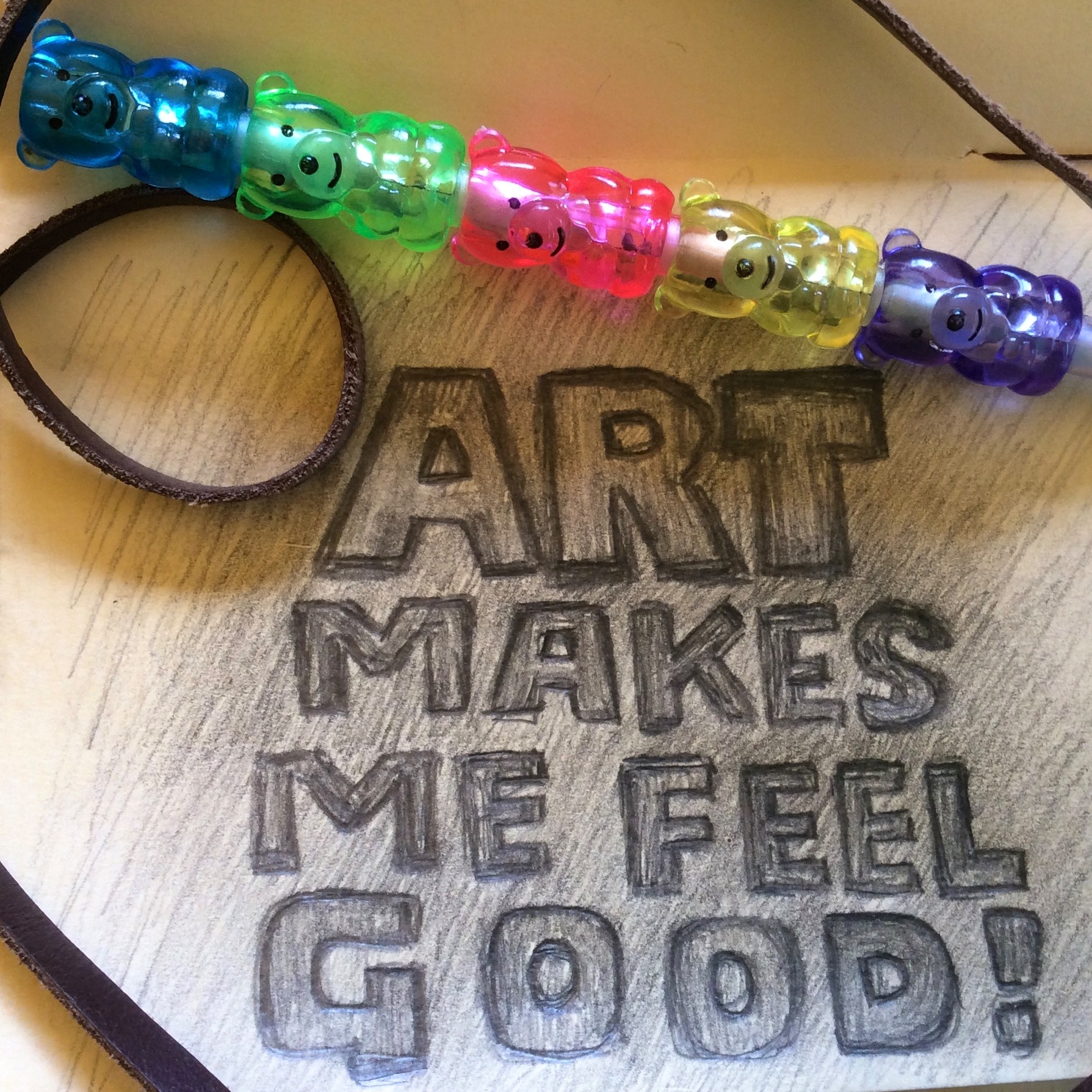 Colorful beaded bracelet with a wooden background engraved with the words 'ART MAKES ME FEEL GOOD!'.