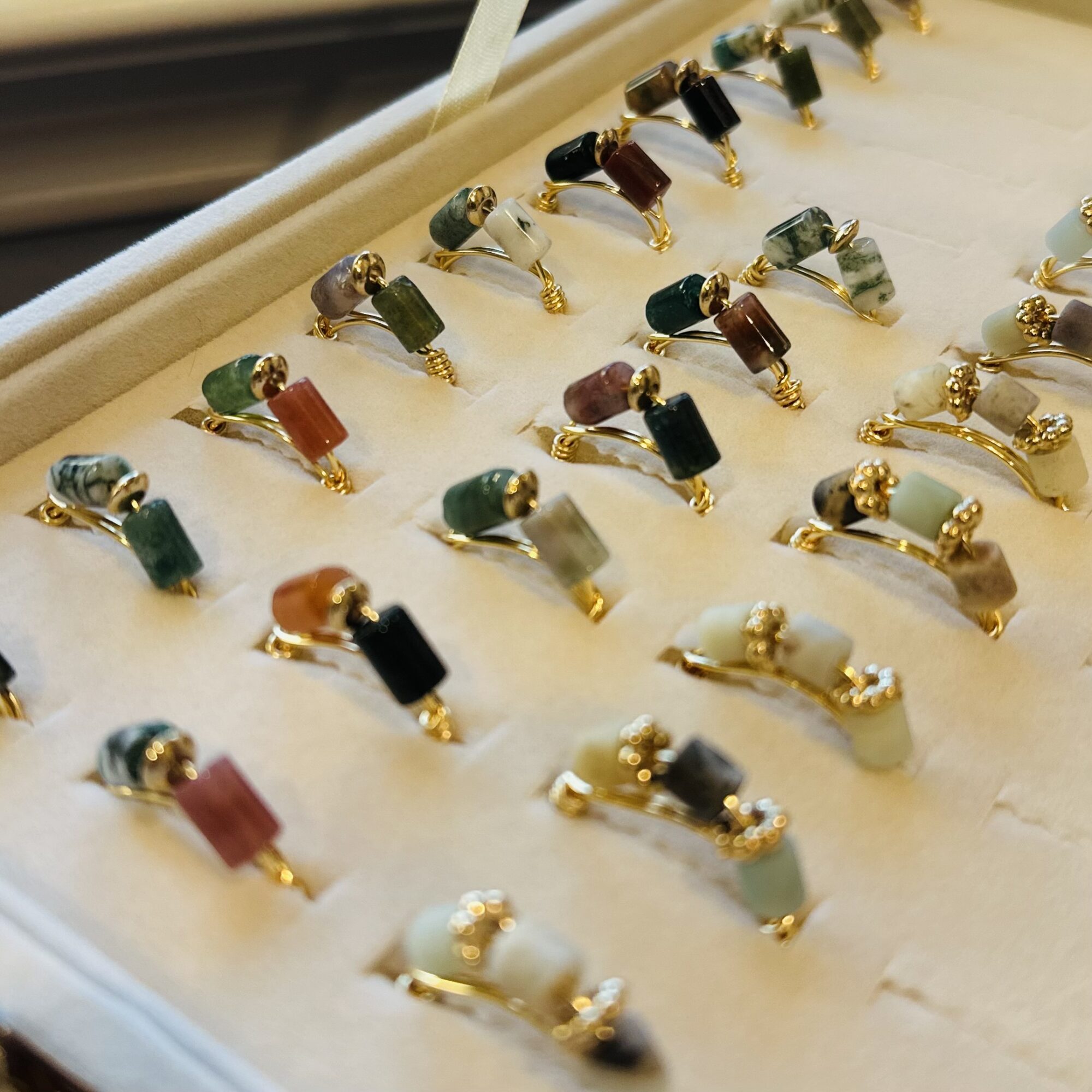 Multiple rings with colorful stones and gold bands displayed on a white surface.