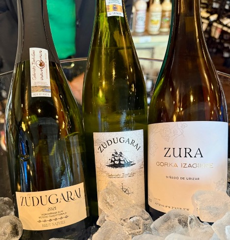 Three wine bottles on ice in a store, with a person in a green shirt in the background.