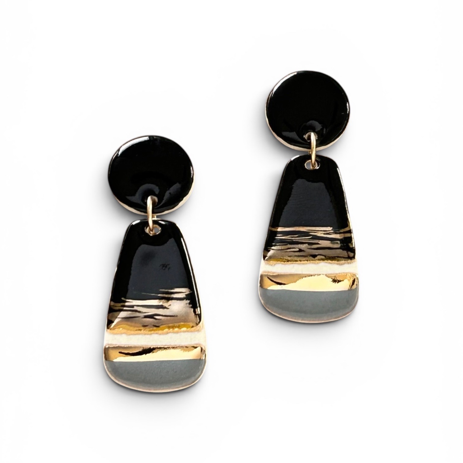 Black and gold drop earrings with a rounded top and elongated, layered design, on a white background.