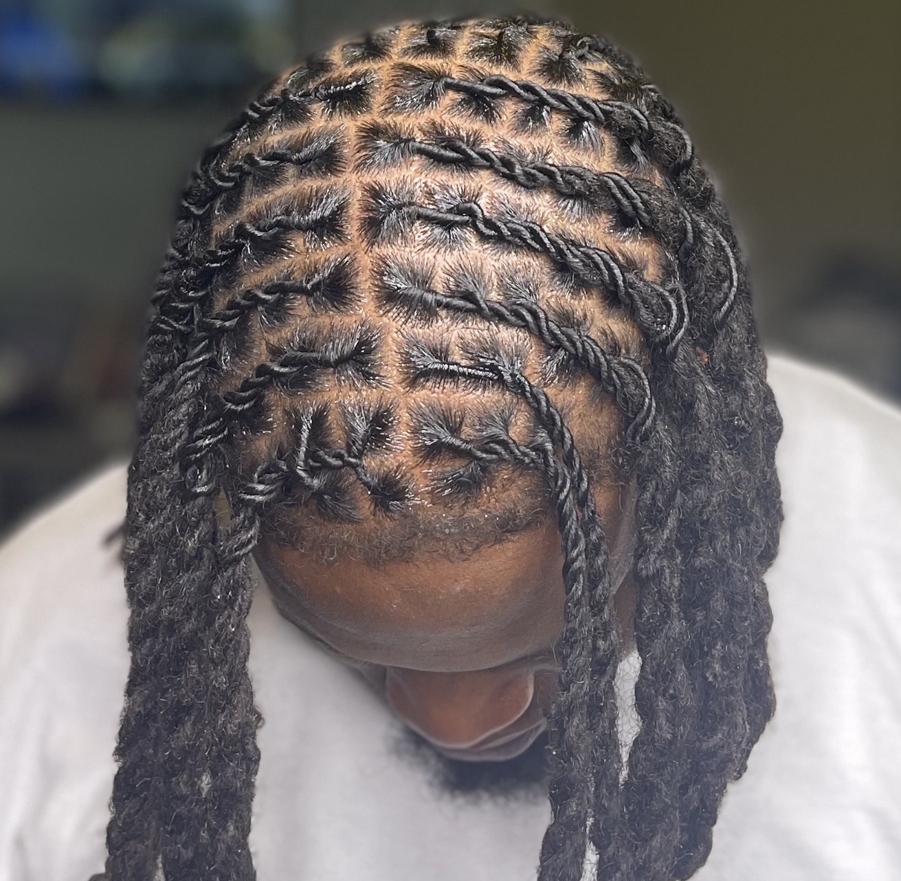 Top view of a person with neatly styled cornrows, showing the scalp and hair pattern, with some loose hair at the ends.