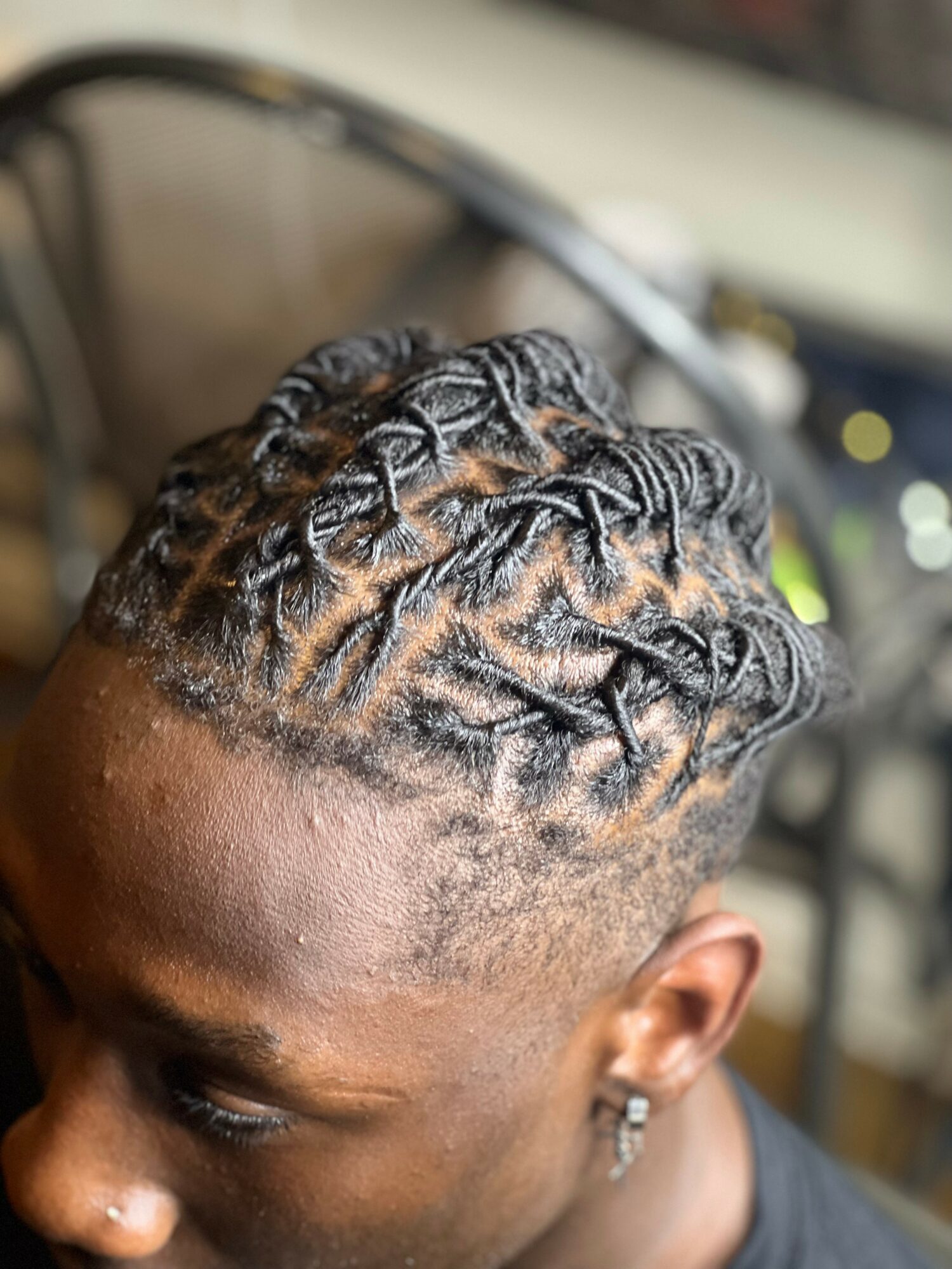 Close-up of a person with freshly styled, intricate braided hair on top, with a blurred background.