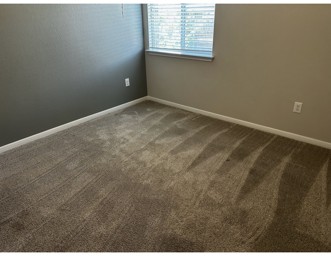 Empty room with beige carpet, two-tone walls, window with blinds, and electrical outlets, viewed from corner.