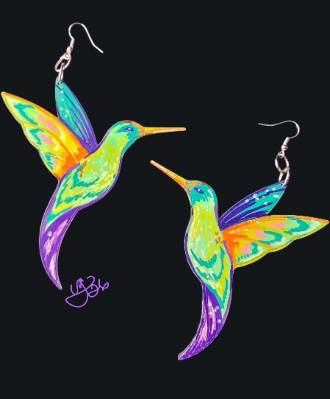 Colorful hummingbird earrings with vibrant wings and long beaks, hanging against a black background.