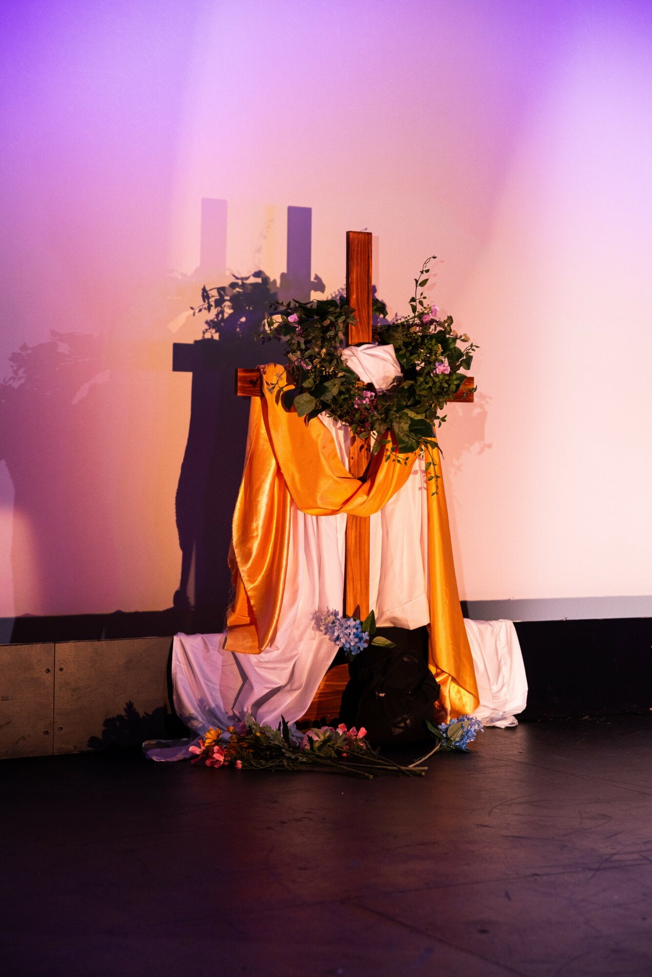Decorated altar with candles, flowers, and draped fabric on stage, with a plain background.