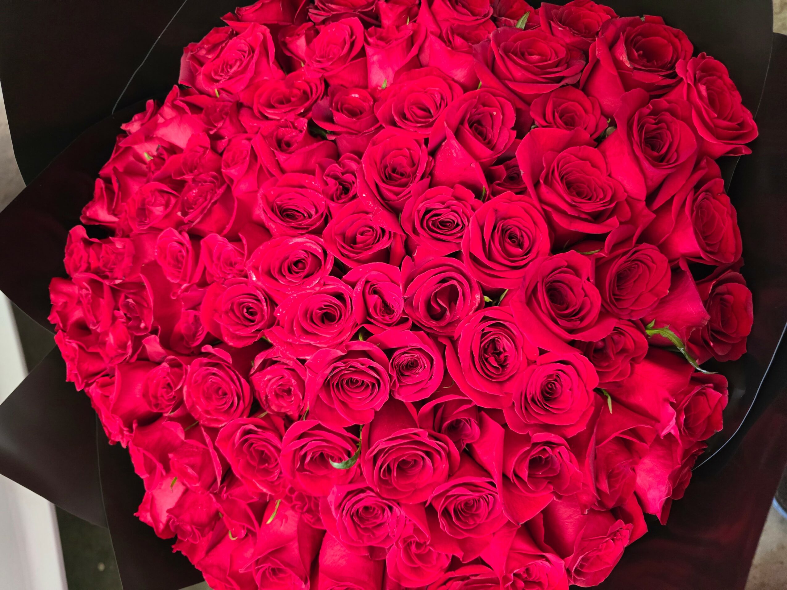 A large bouquet of pink roses arranged in a circular shape, with some petals slightly open.