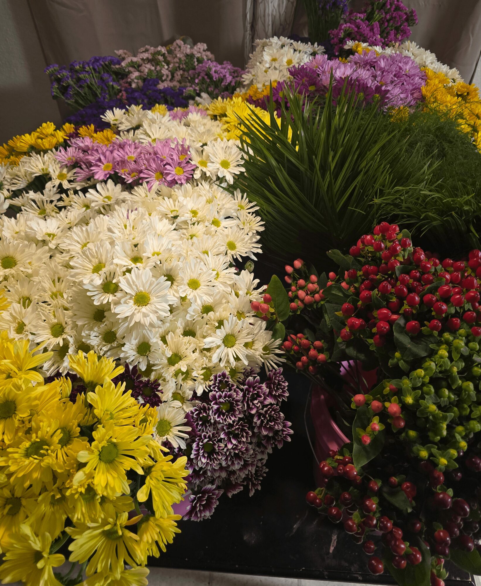 Various colorful flowers including white daisies, yellow, purple, pink, and red blooms arranged together.